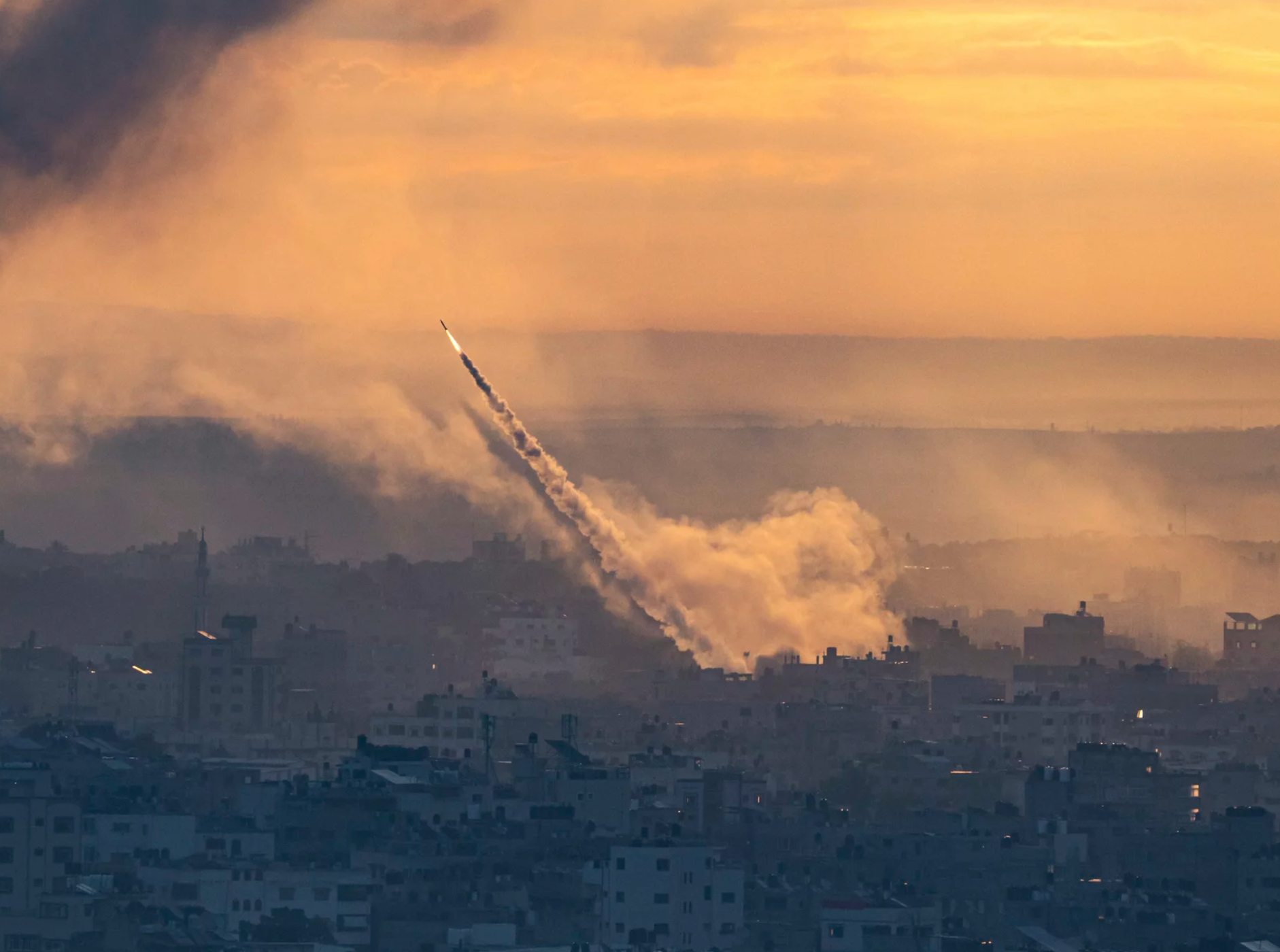 A rocket is being launched over a city at sunset.