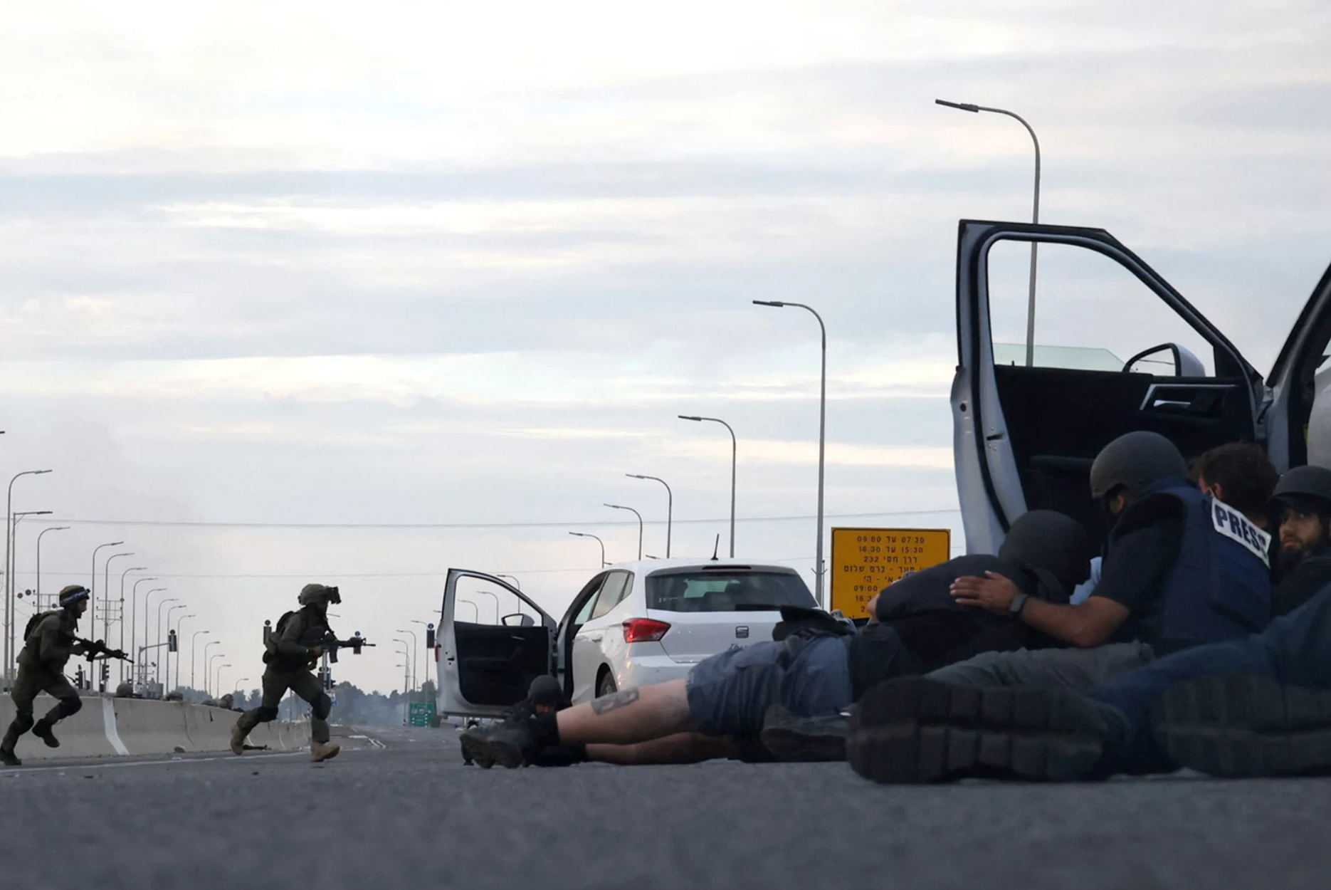 A man is laying on the ground in front of a police car