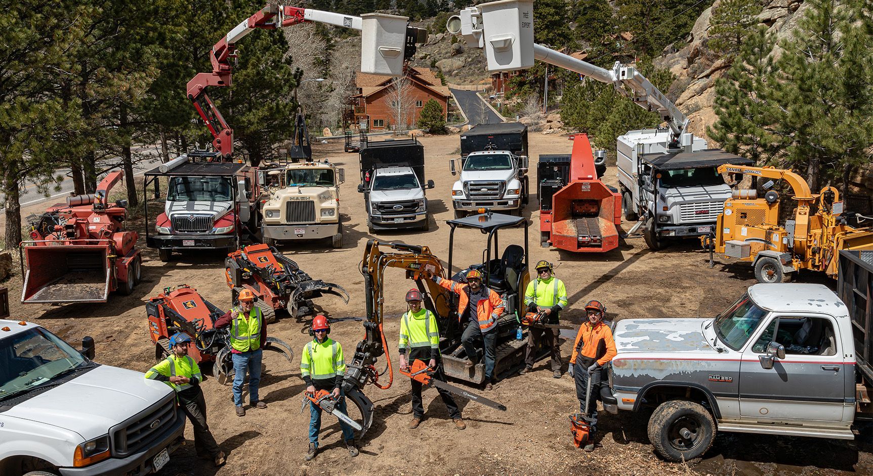 A group of construction workers are posing for a picture with their trucks and machinery.