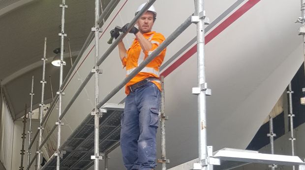 Marine scaffold setup for boat restoration, providing safe platform access in indoor ship maintenance shed.
