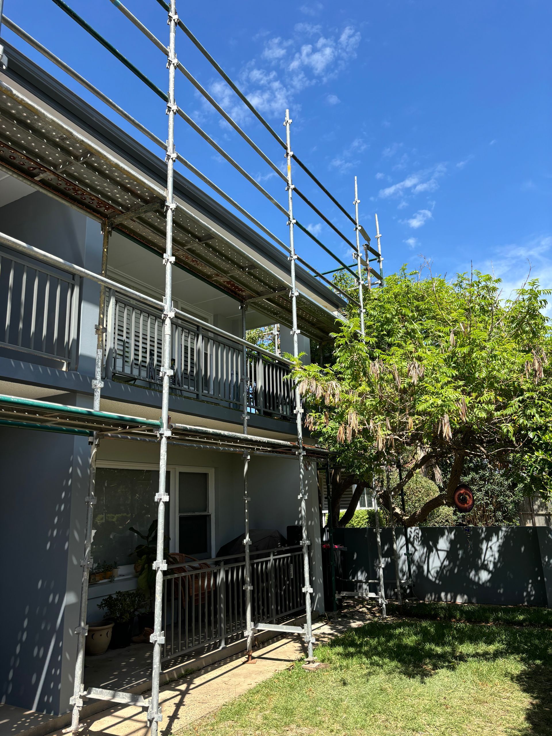 Scaffold setup on two-storey house providing roof access for repairs.