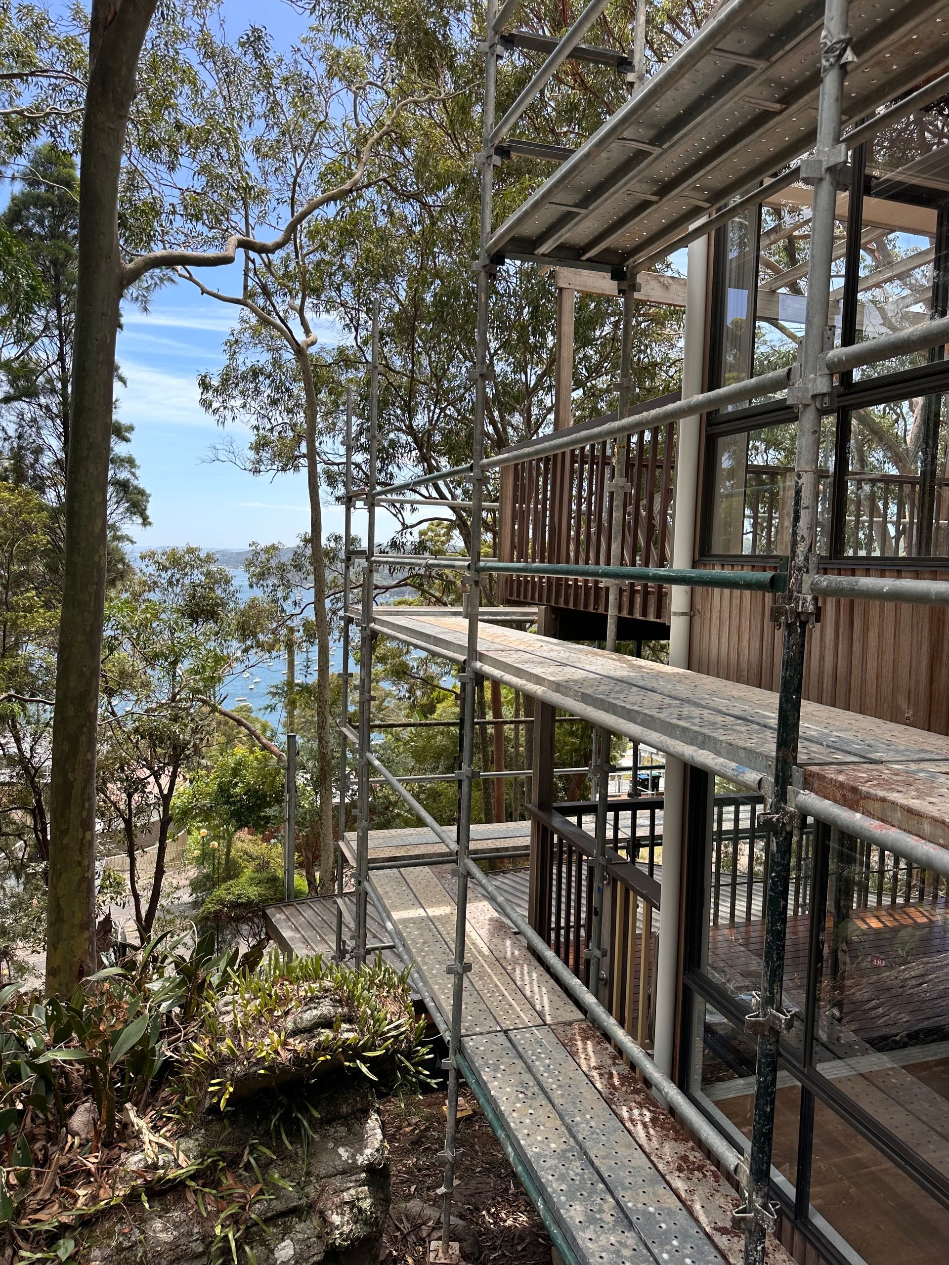 Scaffold deck overlooking waterfront bushland, providing safe access to multi-level timber home