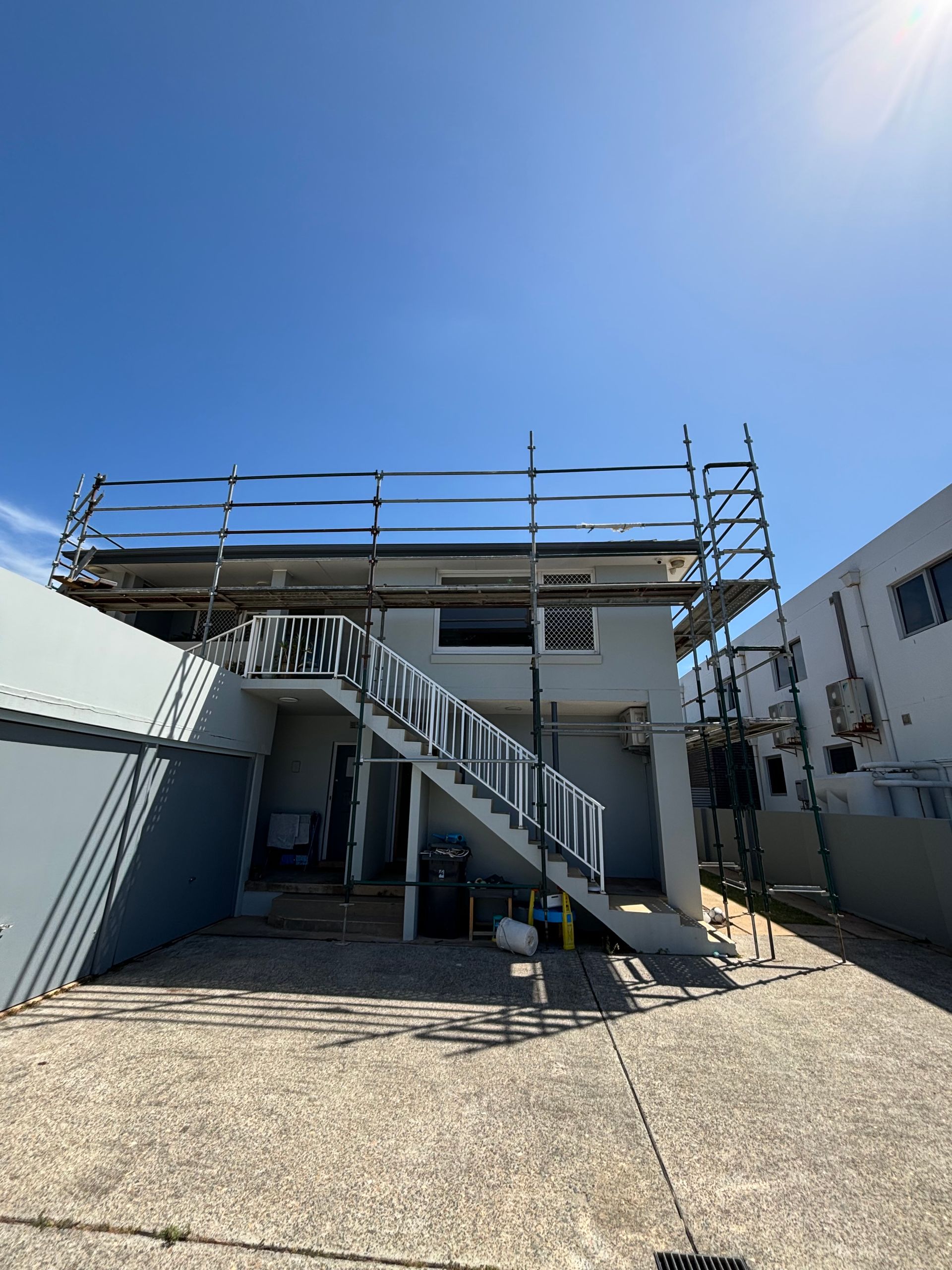 Scaffold installed around full residential building, including over stairs and garage.