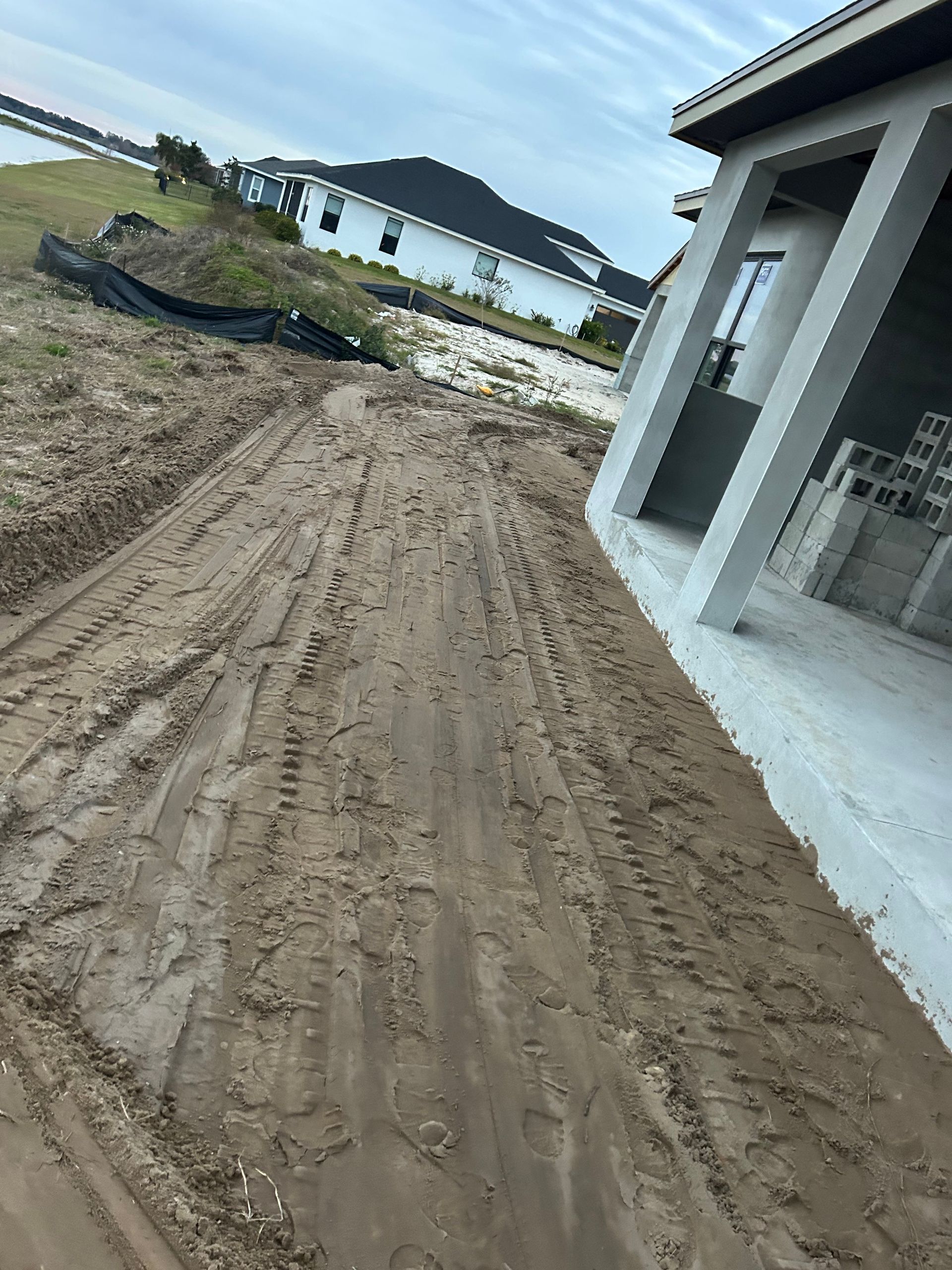 A dirt road leading to a house under construction