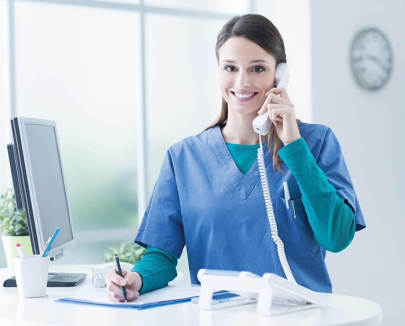 Una enfermera está sentada en un escritorio hablando por teléfono.