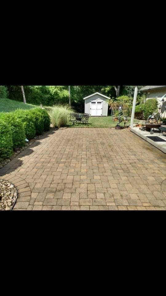 A brick driveway with a white shed in the background.