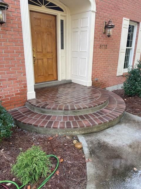 A brick walkway leading to the front door of a brick house.