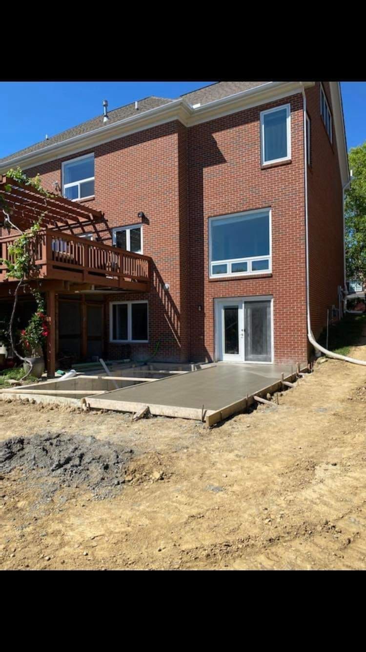 A large brick house with a concrete patio in front of it.