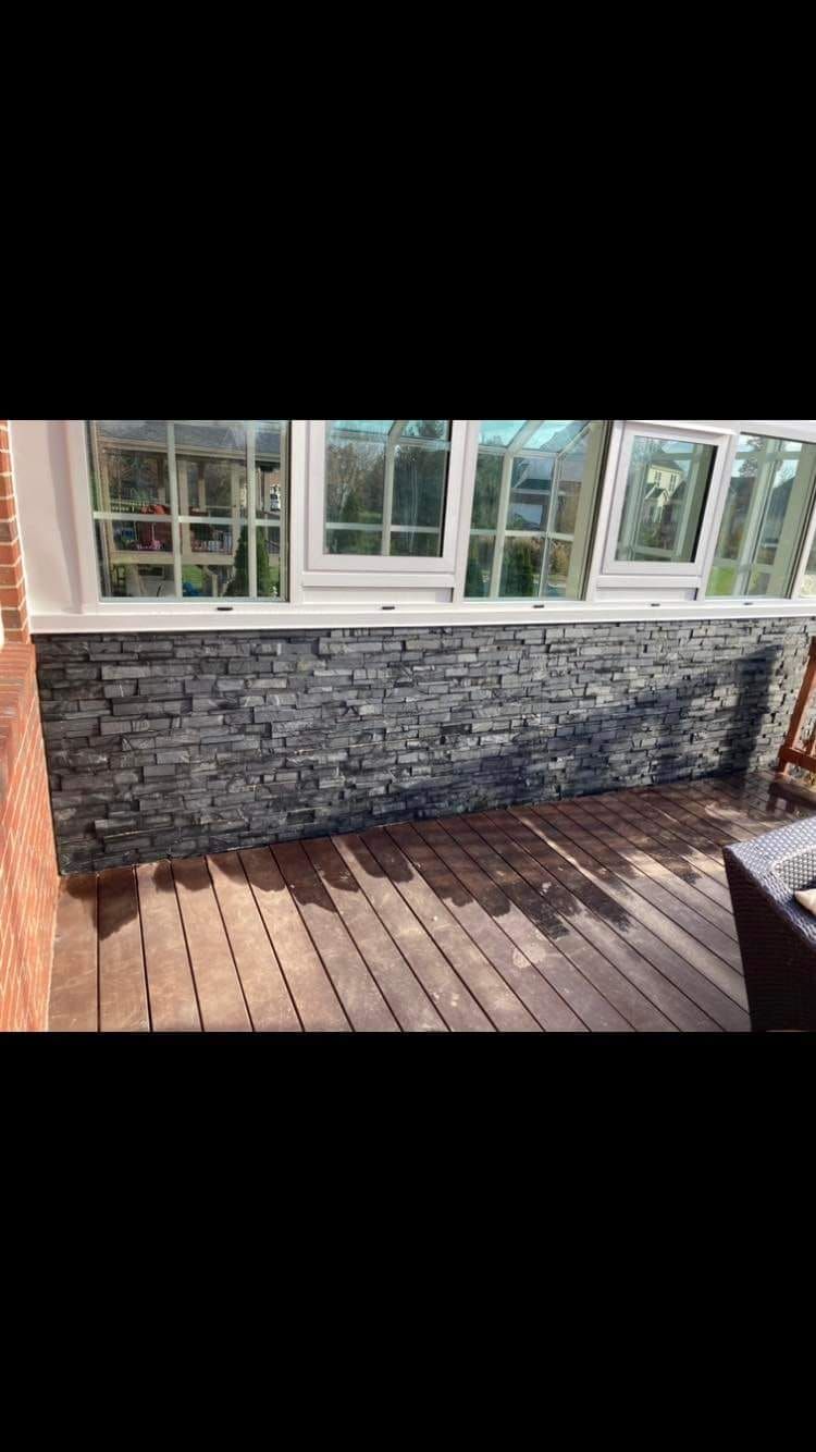 A brick wall with a wooden deck in front of it.