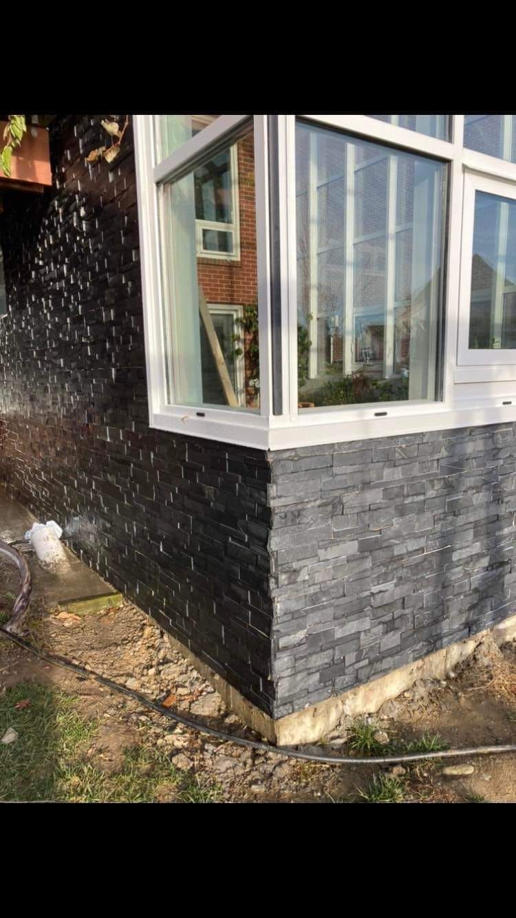 A house with a large window and a black brick wall.