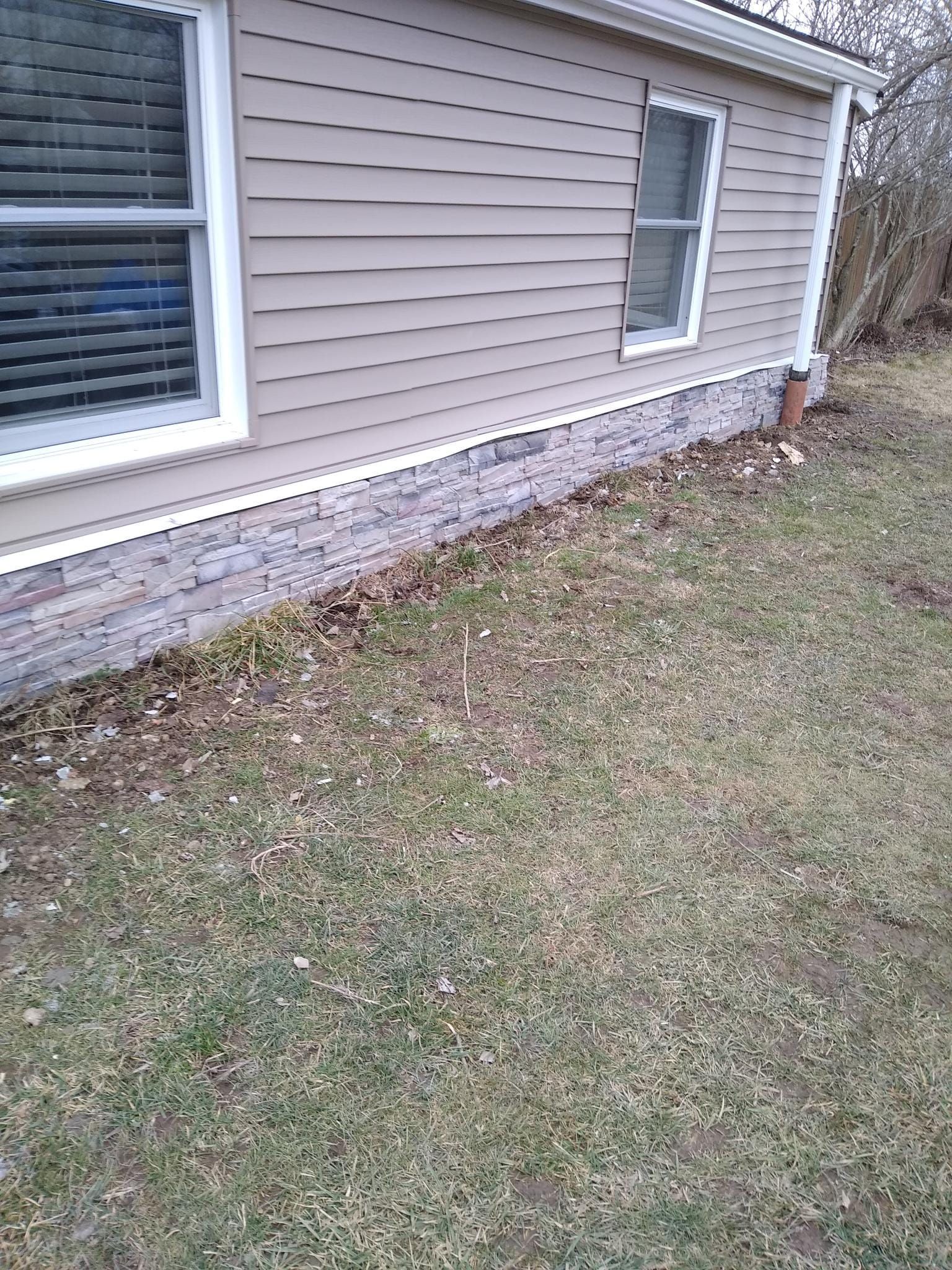 A house with a brick foundation is sitting on top of a lush green lawn.