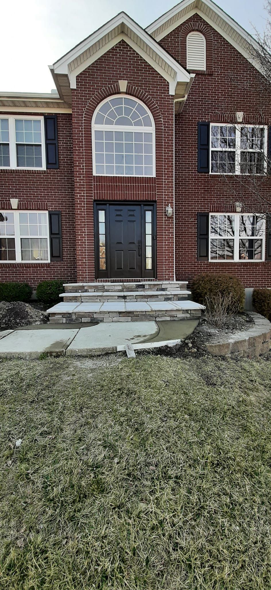 A large brick house with stairs leading up to the front door.