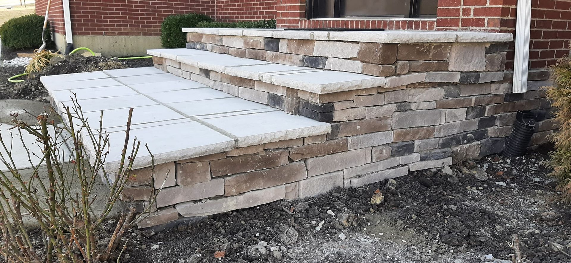 A stone wall with steps leading up to a brick house.