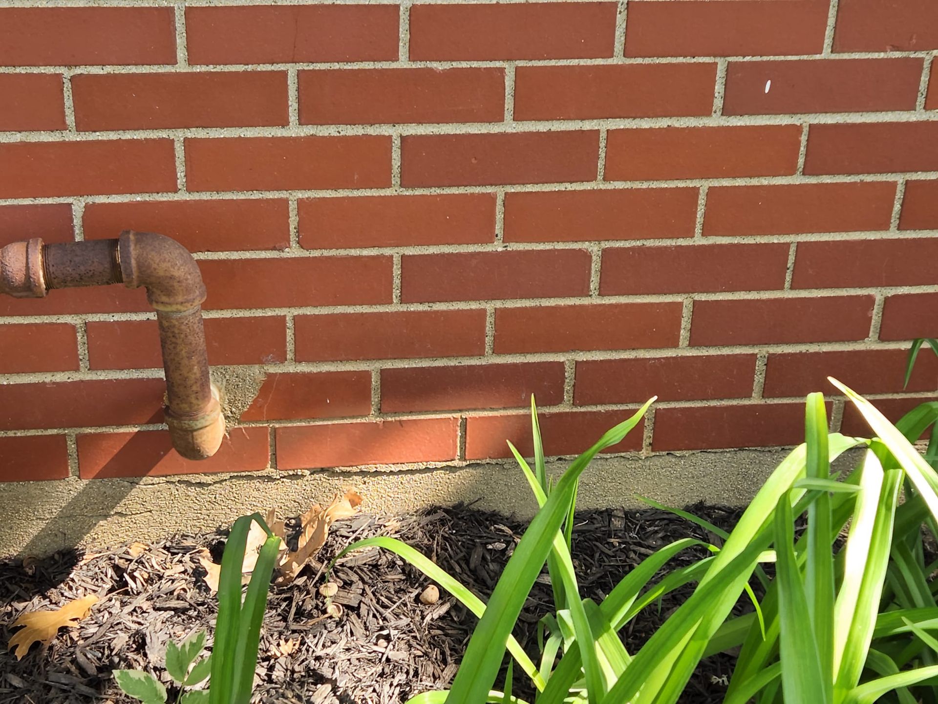 A brick wall with a rusty pipe coming out of it