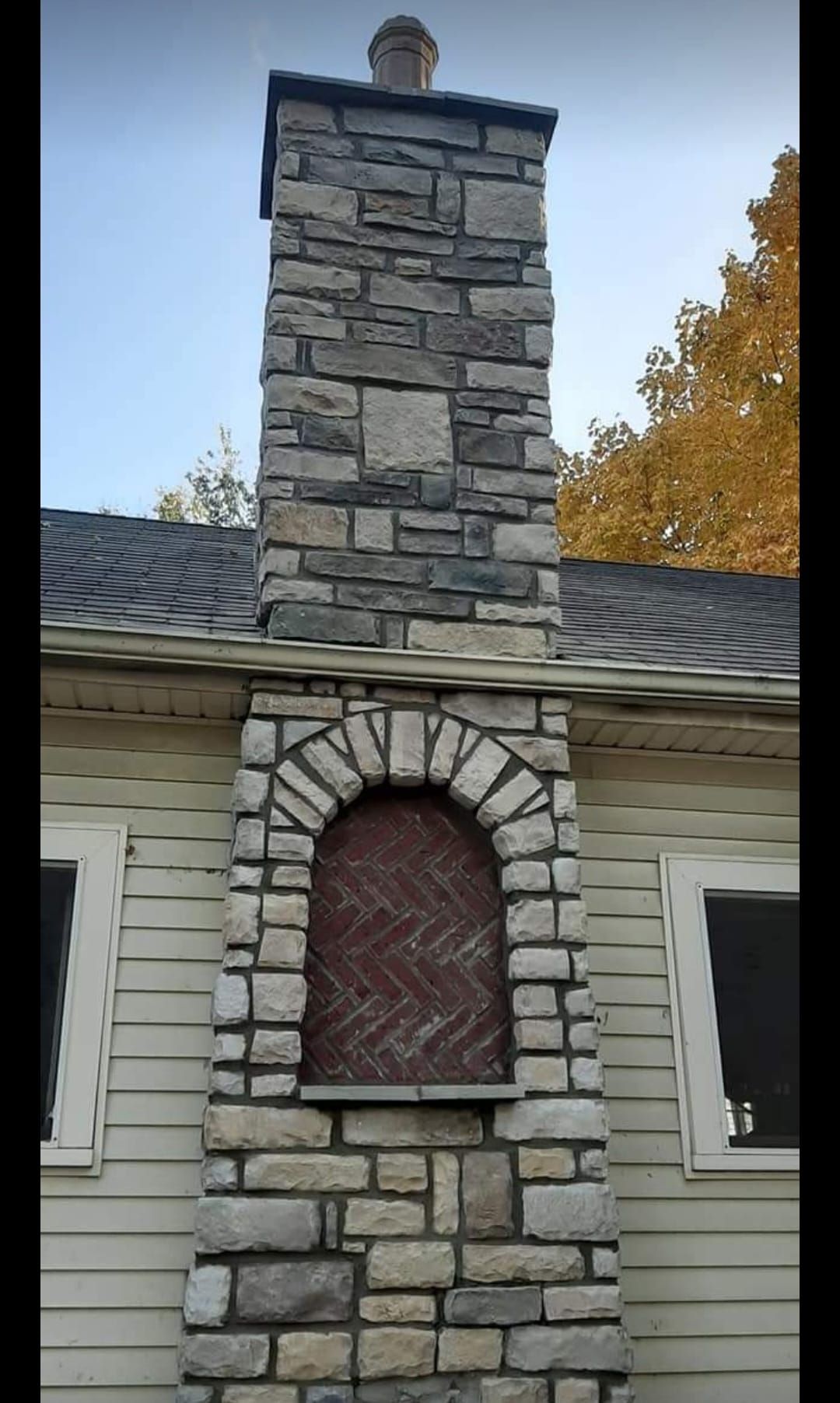 A large stone chimney is on the side of a house.