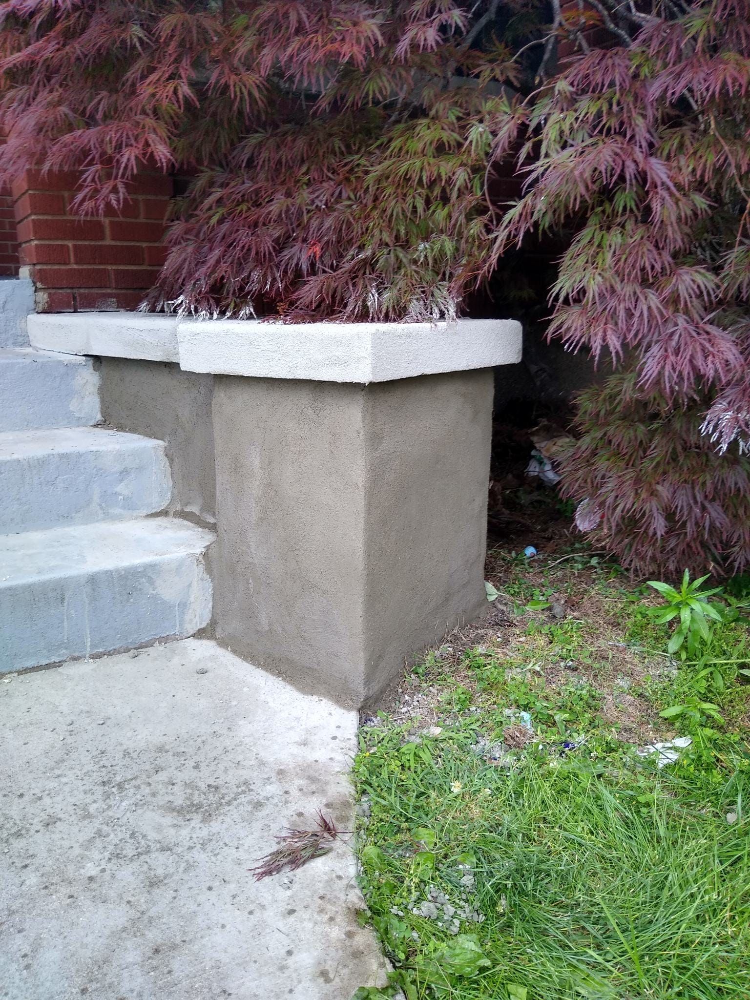 A concrete pillar next to a set of stairs with a tree in the background.
