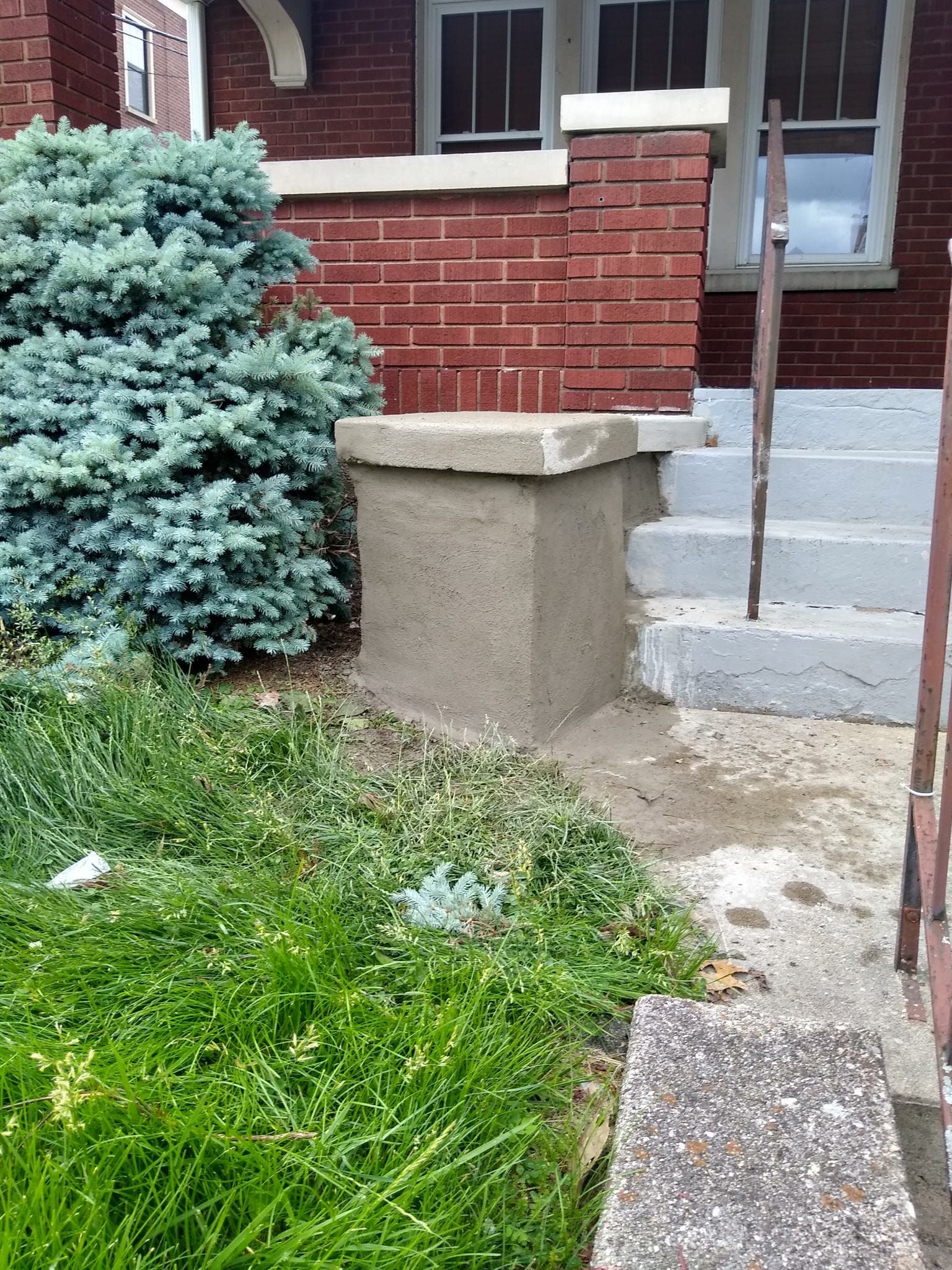 A brick house with a concrete pillar in front of it