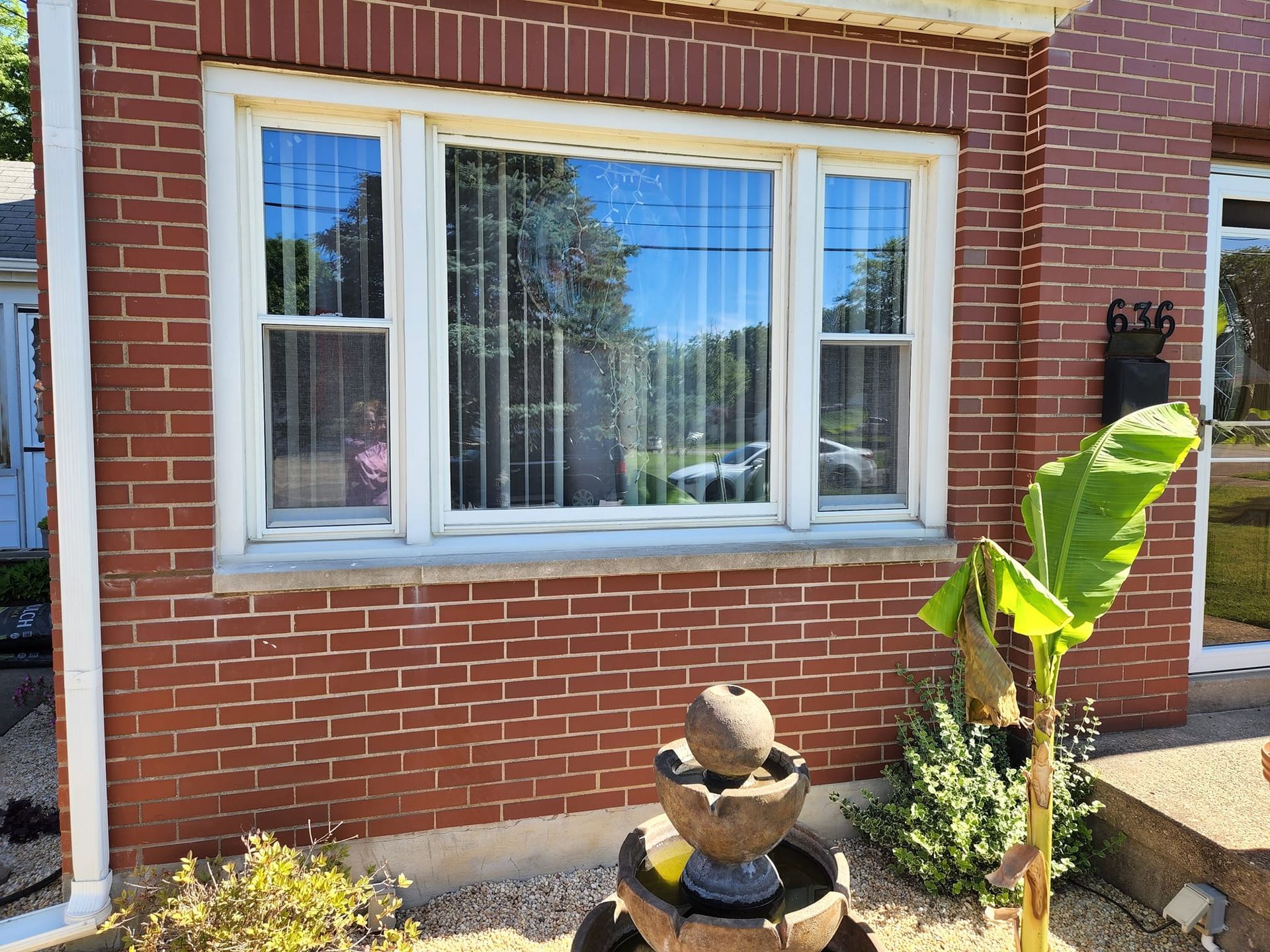 A brick house with a large window and a fountain in front of it.