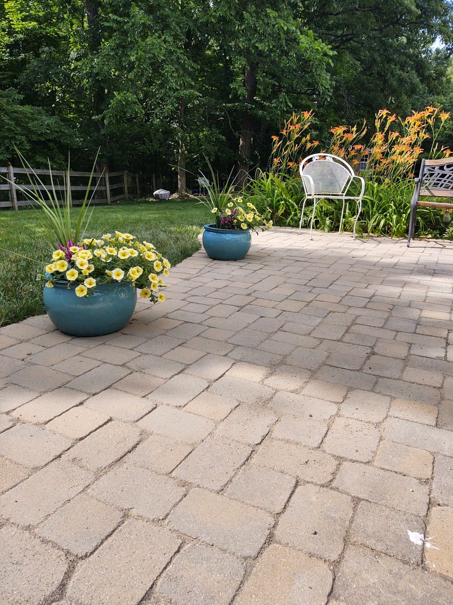 A patio with two potted plants and a bench.