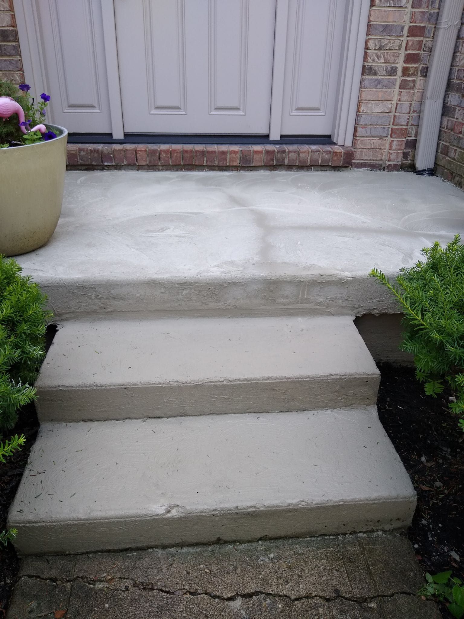 A set of concrete steps leading up to a front door of a house.