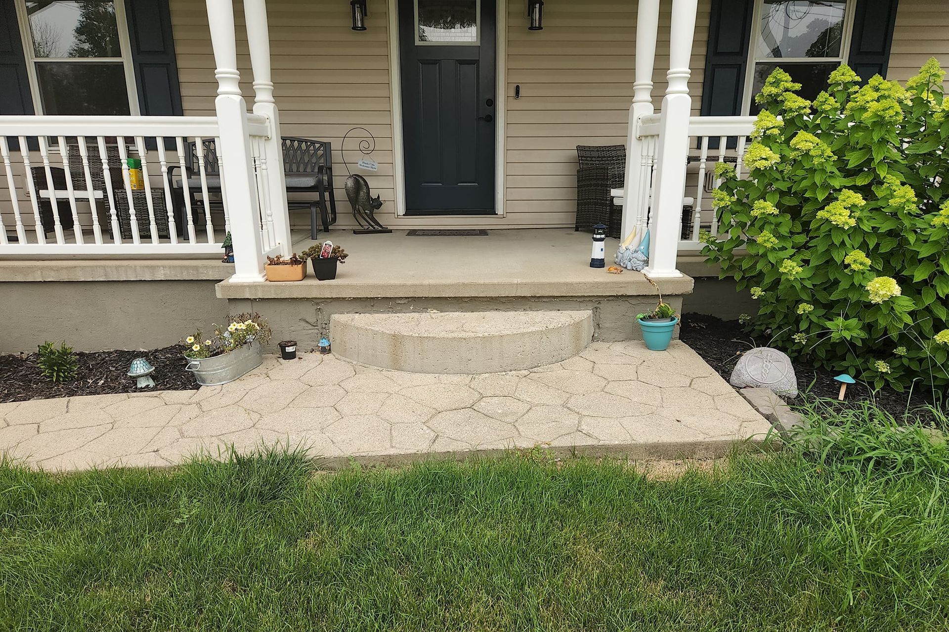 The front porch of a house with a blue door and white railing