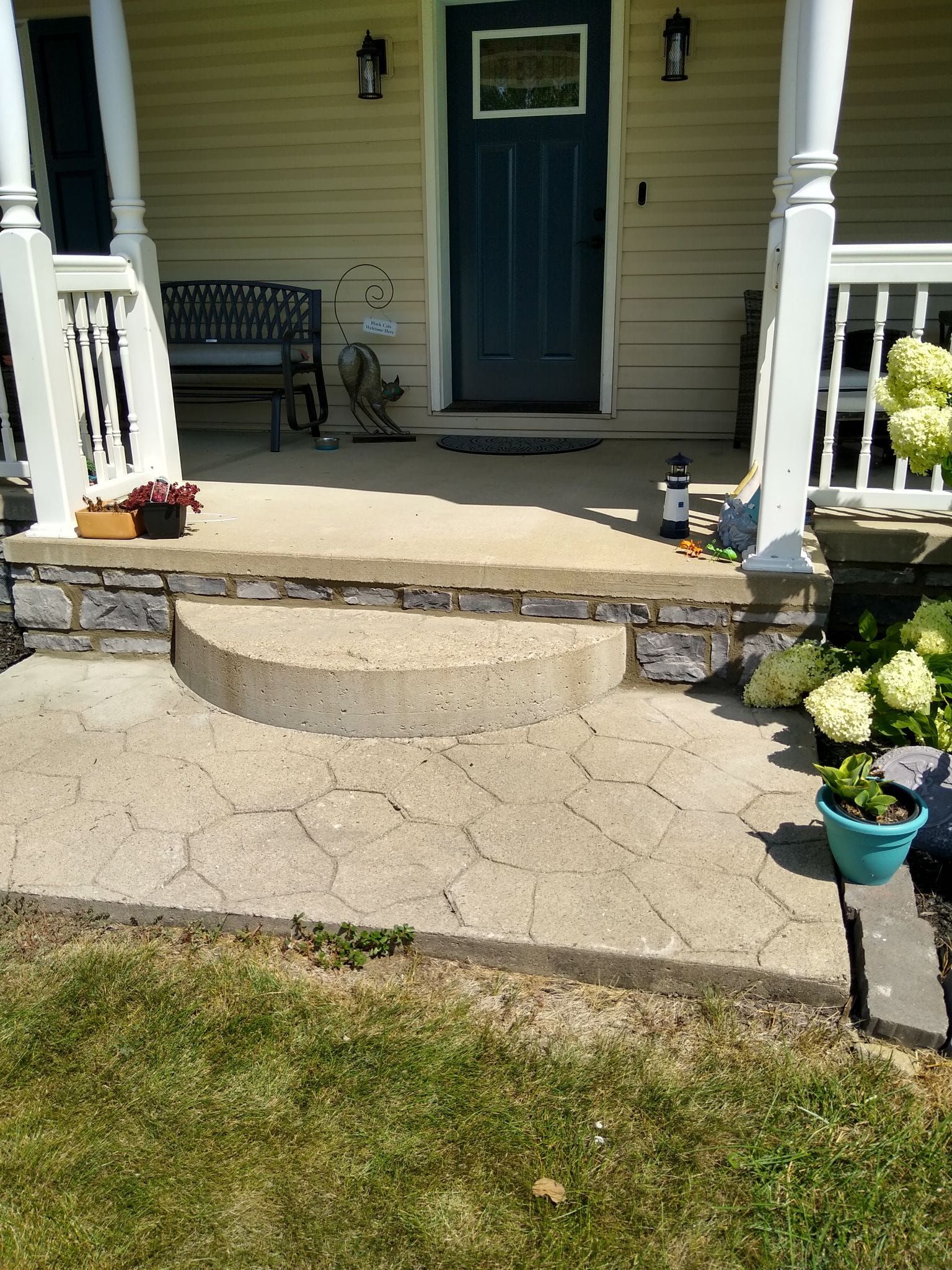 The front porch of a house with a blue door and steps leading up to it.