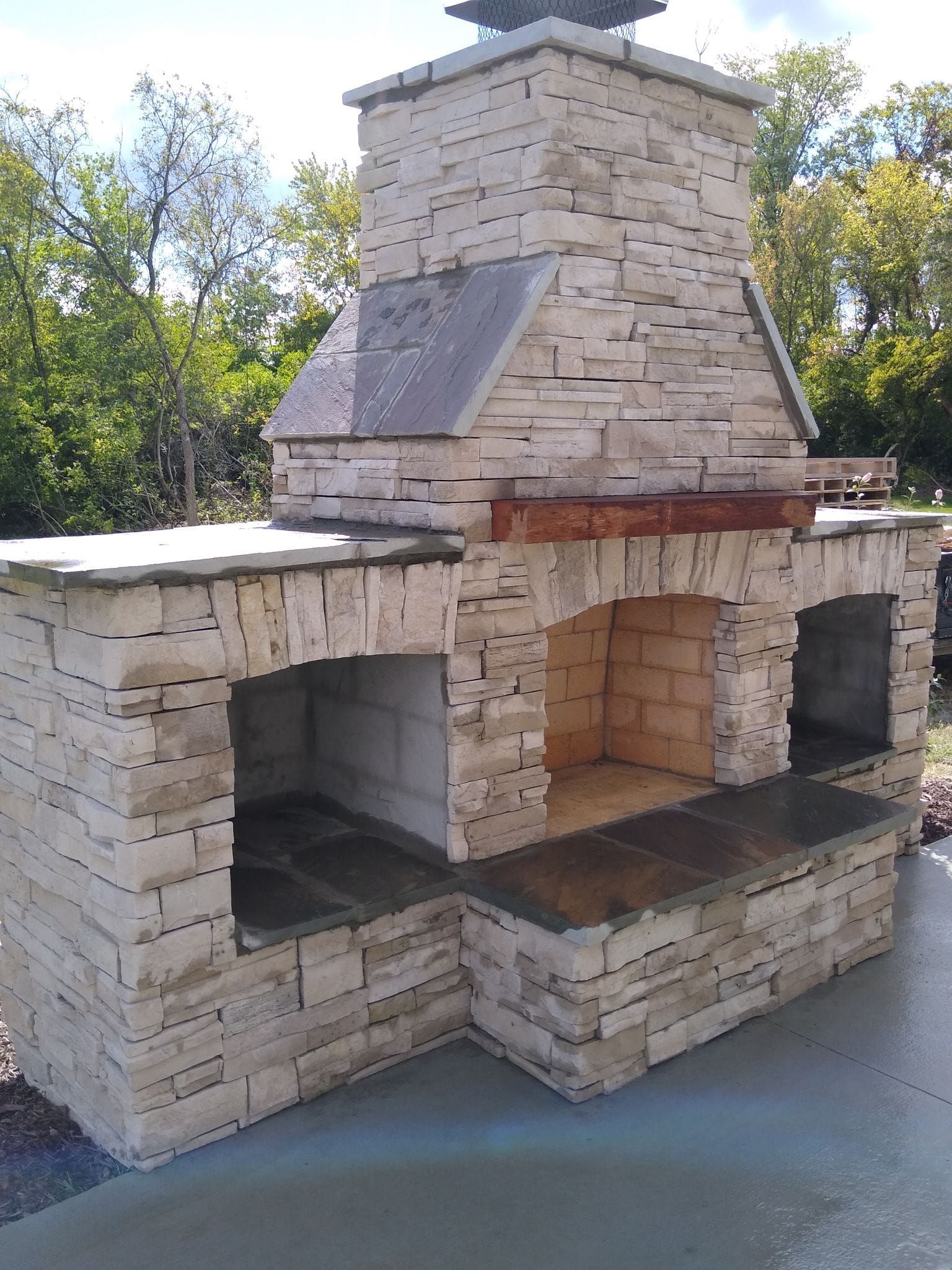 A large brick fireplace is sitting on top of a concrete patio.