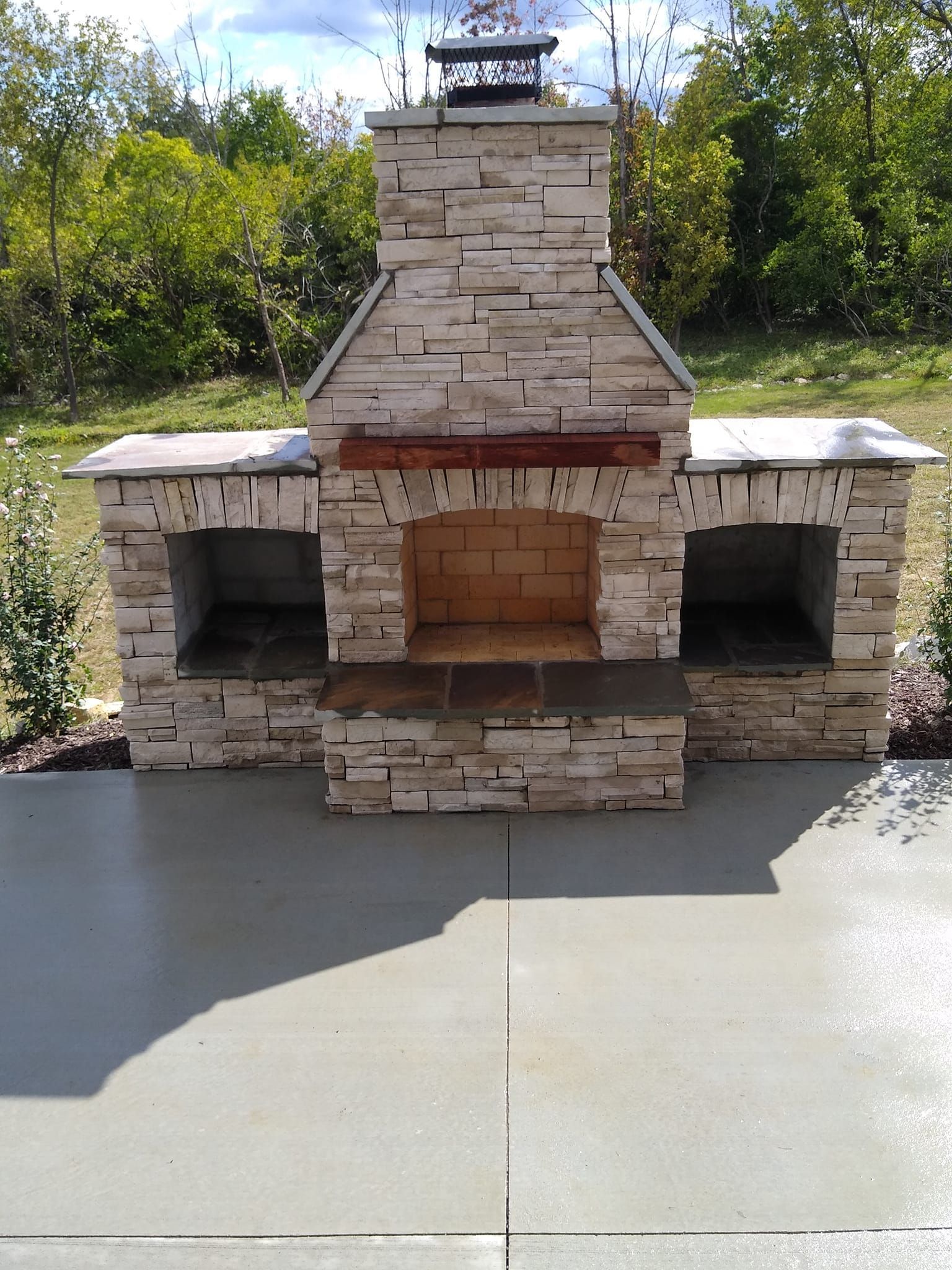 A stone fireplace is sitting on top of a concrete patio.