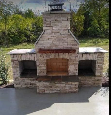 A stone fireplace is sitting on top of a concrete patio.