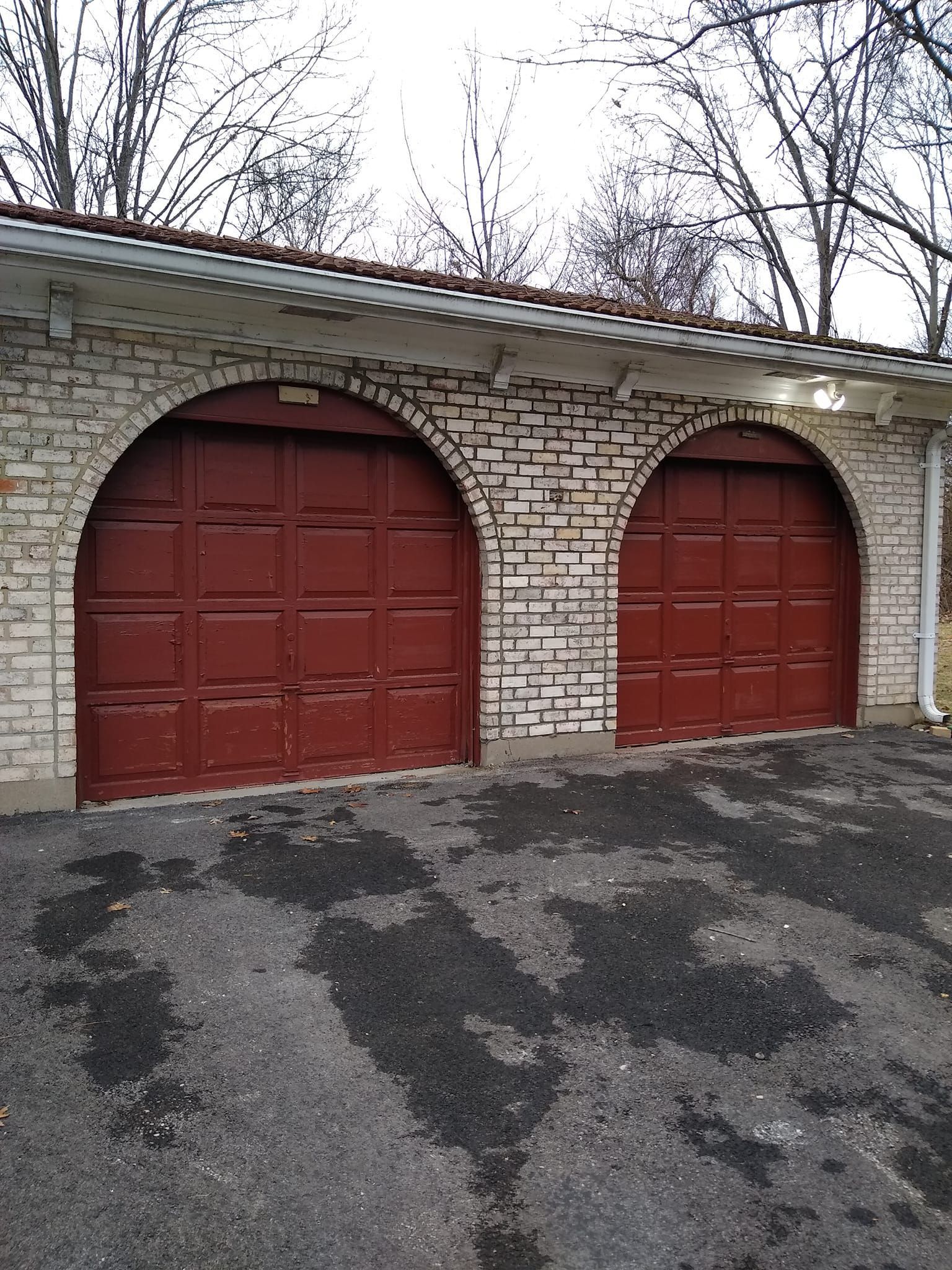 Two red garage doors are on a white brick building.