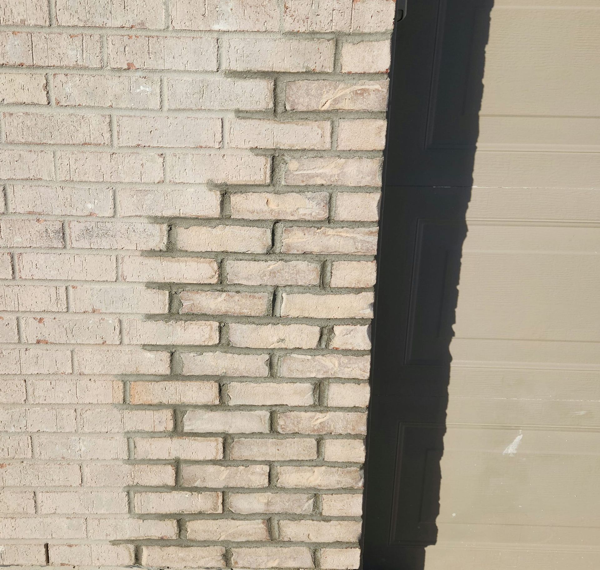 A white brick wall with a black trim on the corner