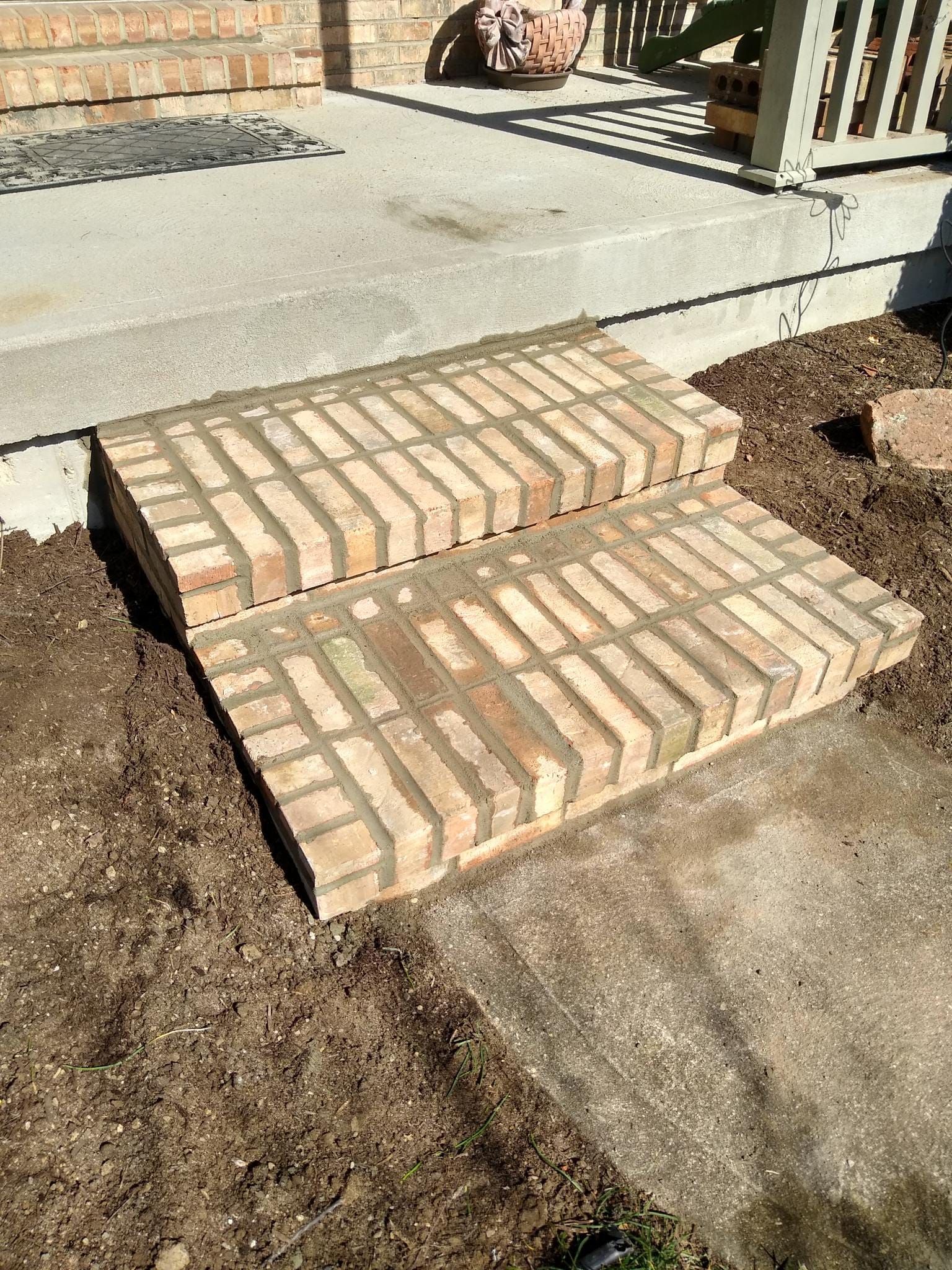 A set of brick steps sitting on top of a dirt ground.