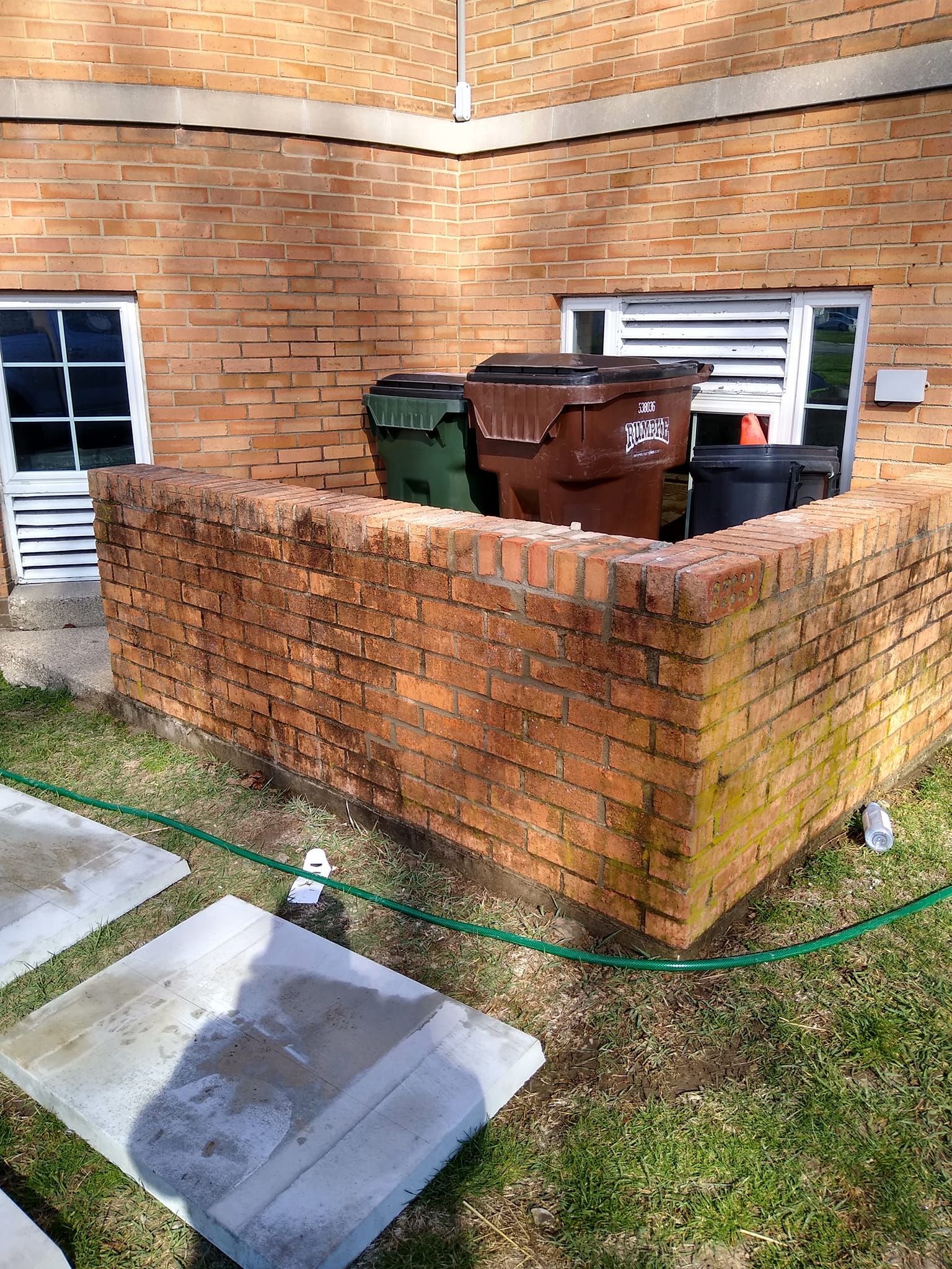 A bunch of trash cans are sitting on top of a brick wall.