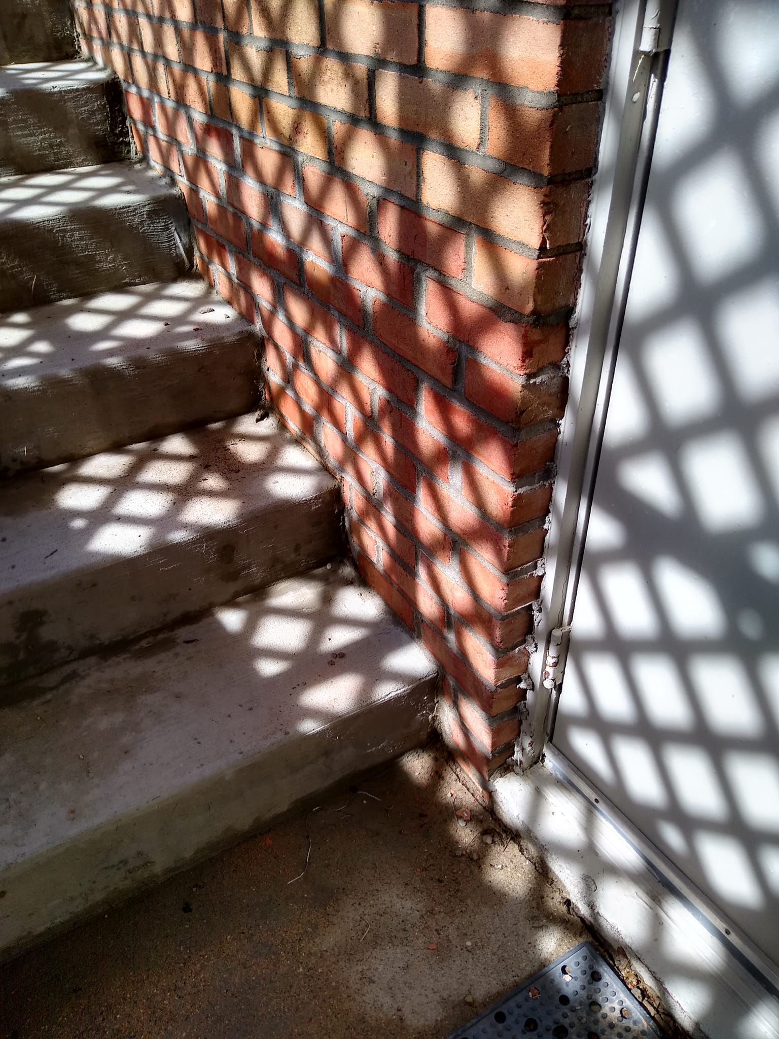 A brick wall is casting a shadow on a set of stairs.