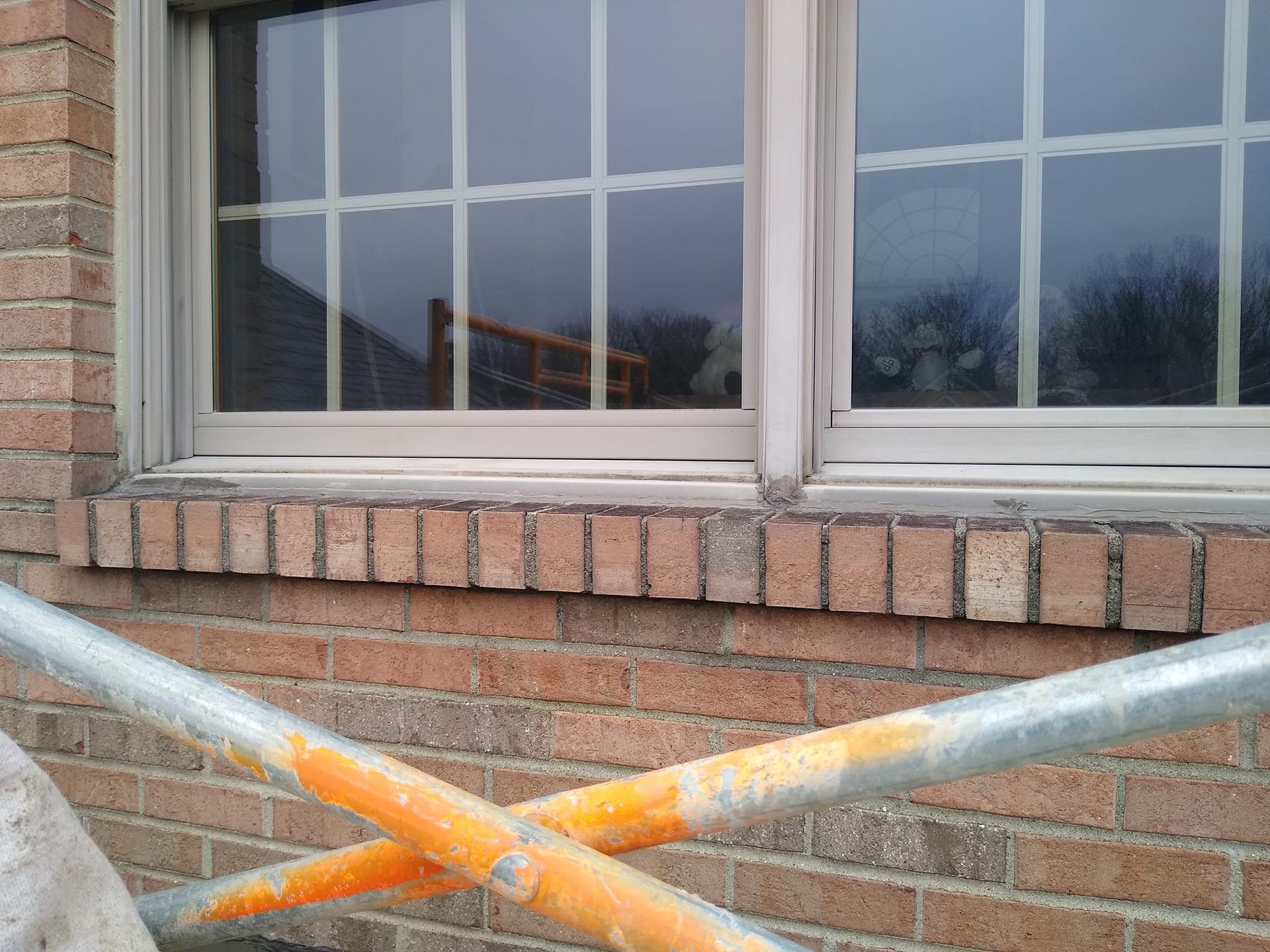A brick building with a window and a scaffolding in front of it.