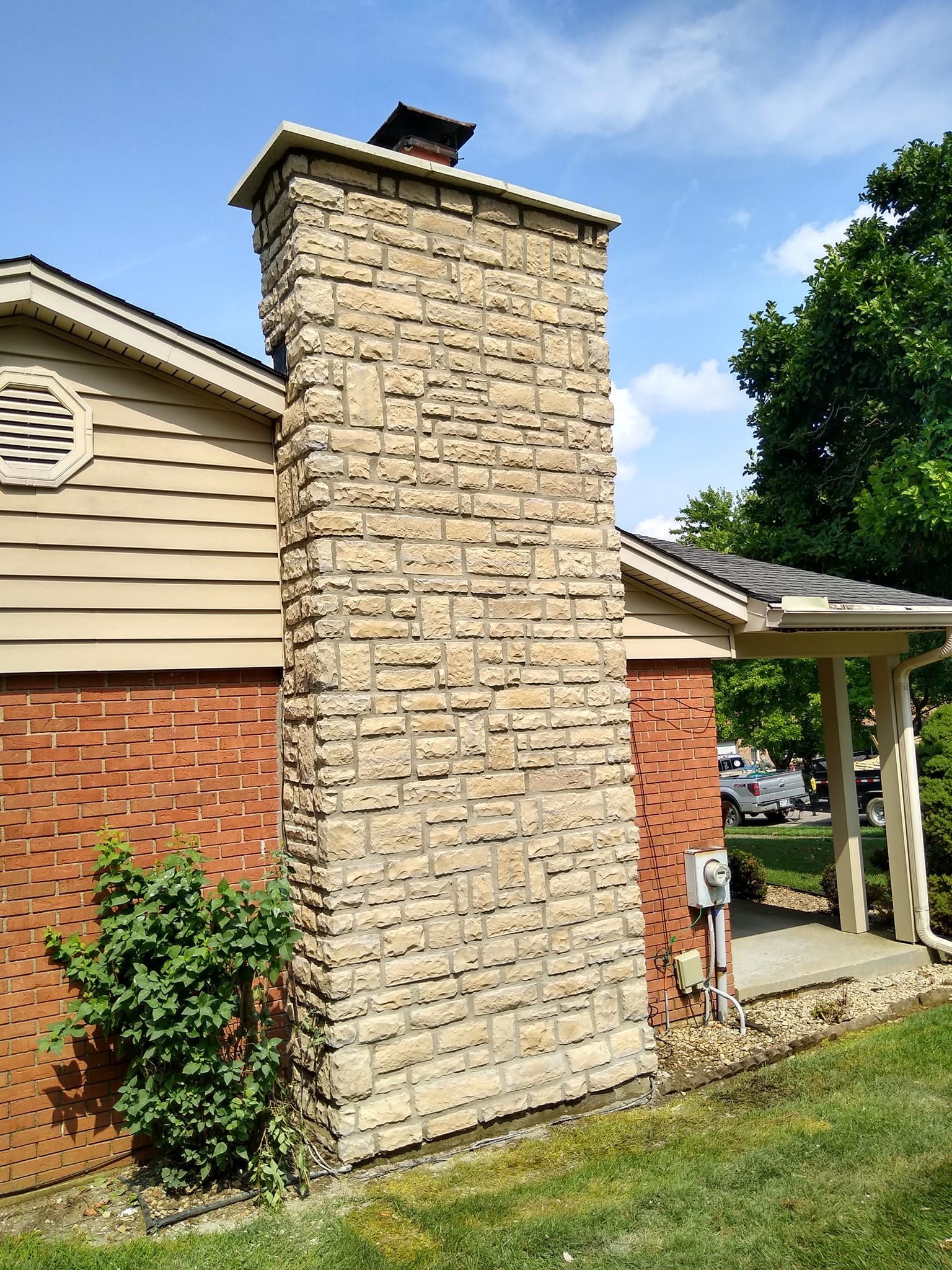 A large stone chimney is on the side of a house.