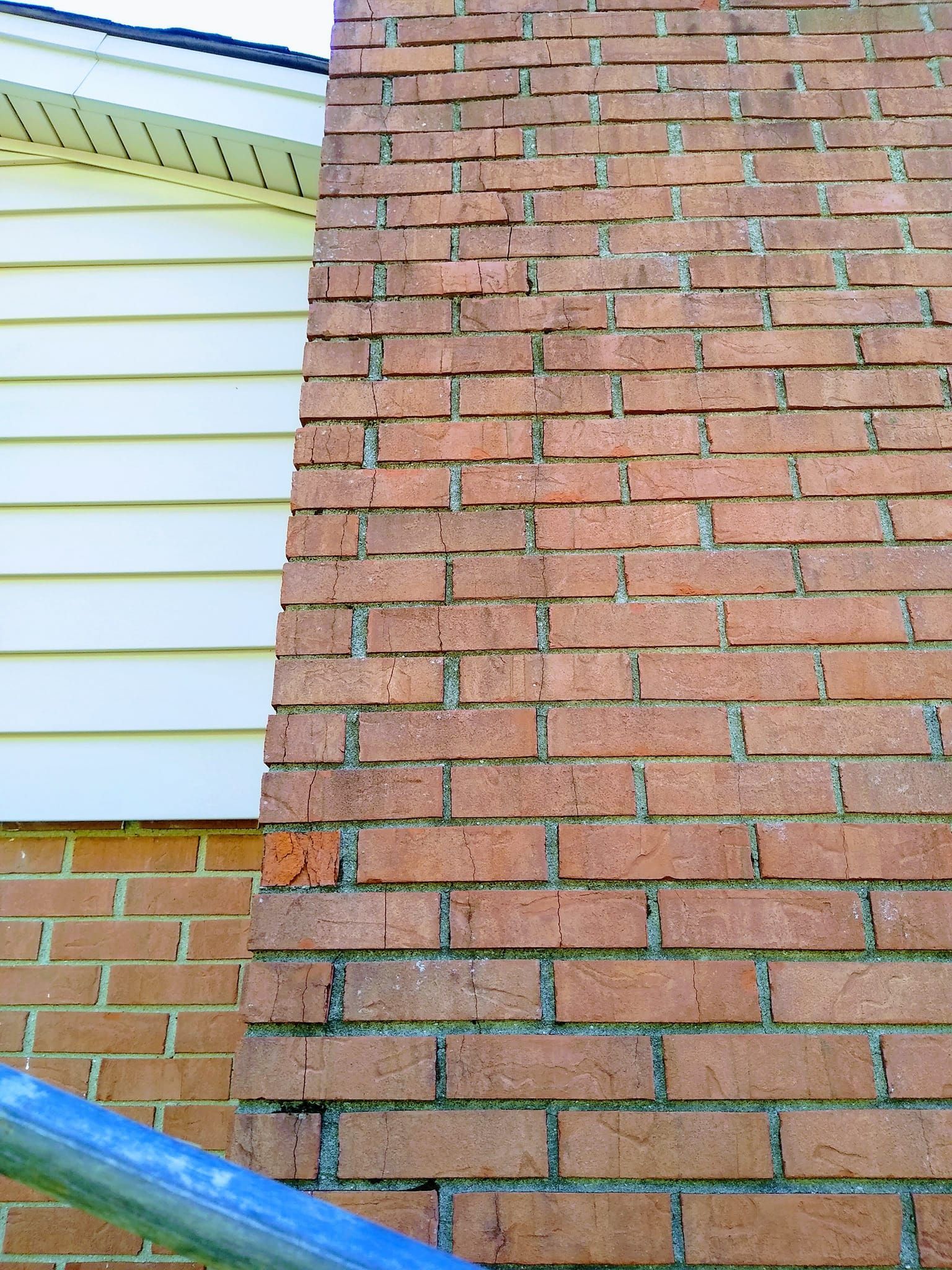 A close up of a brick wall next to a white house.