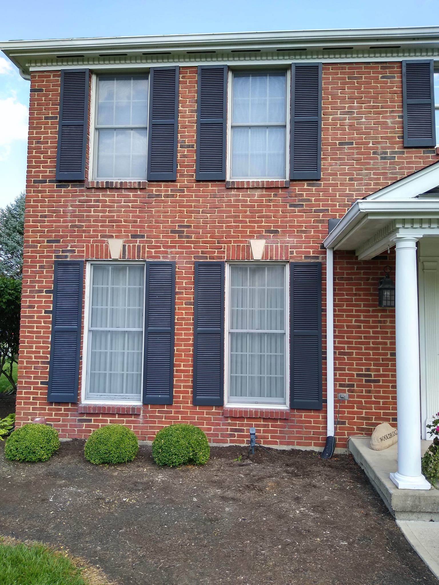 A brick house with black shutters on the windows