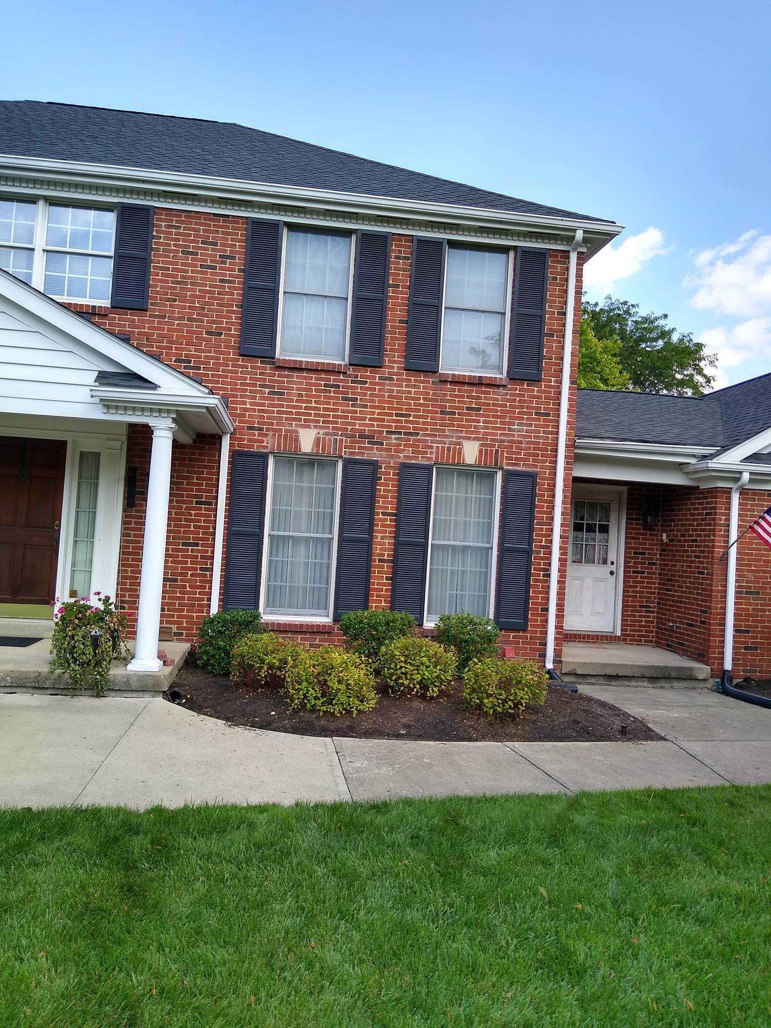 A brick house with black shutters on the windows
