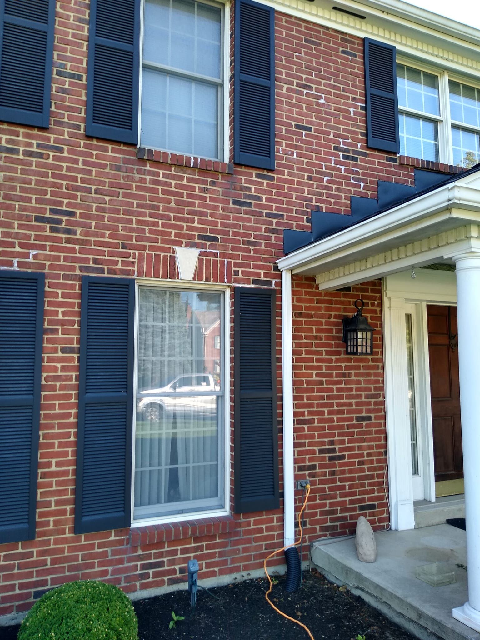A red brick house with black shutters on the windows