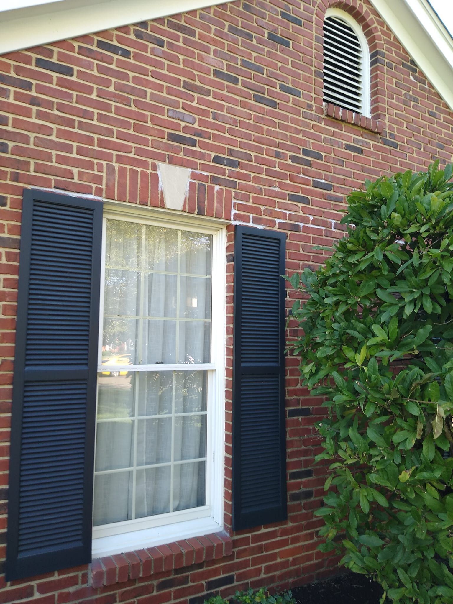 A red brick house with black shutters on the windows
