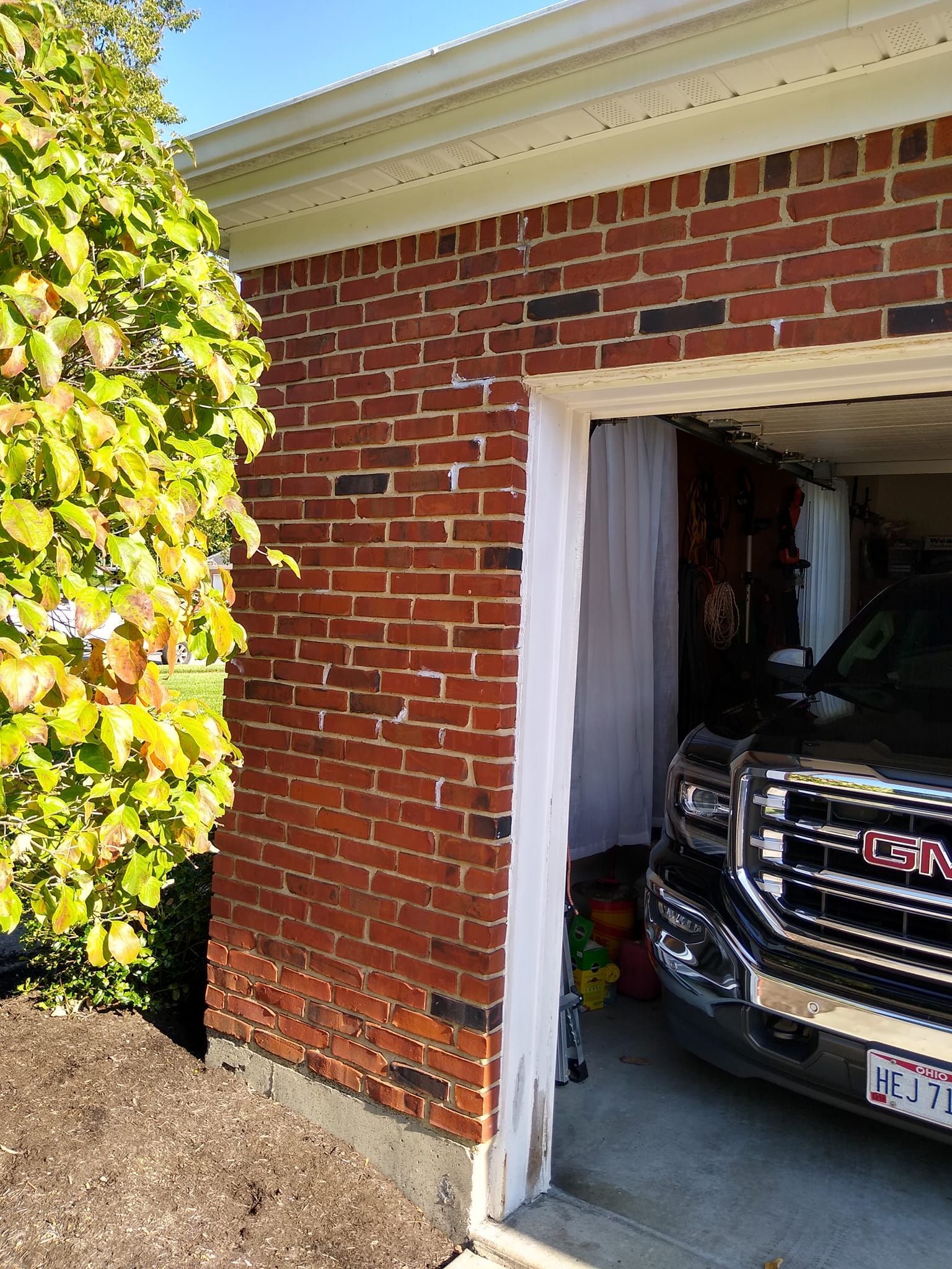 A gmc truck is parked in a garage next to a brick building.