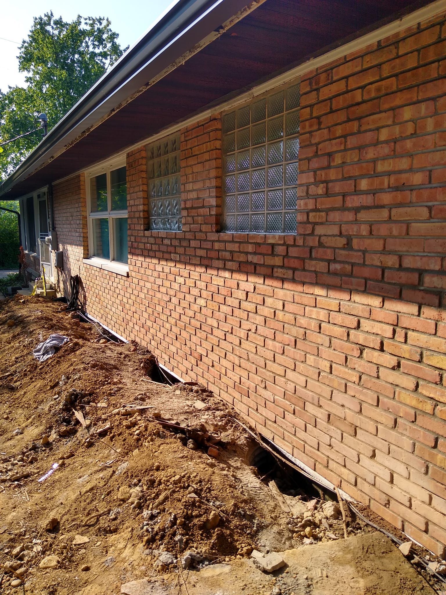 A brick house with a hole in the ground in front of it.