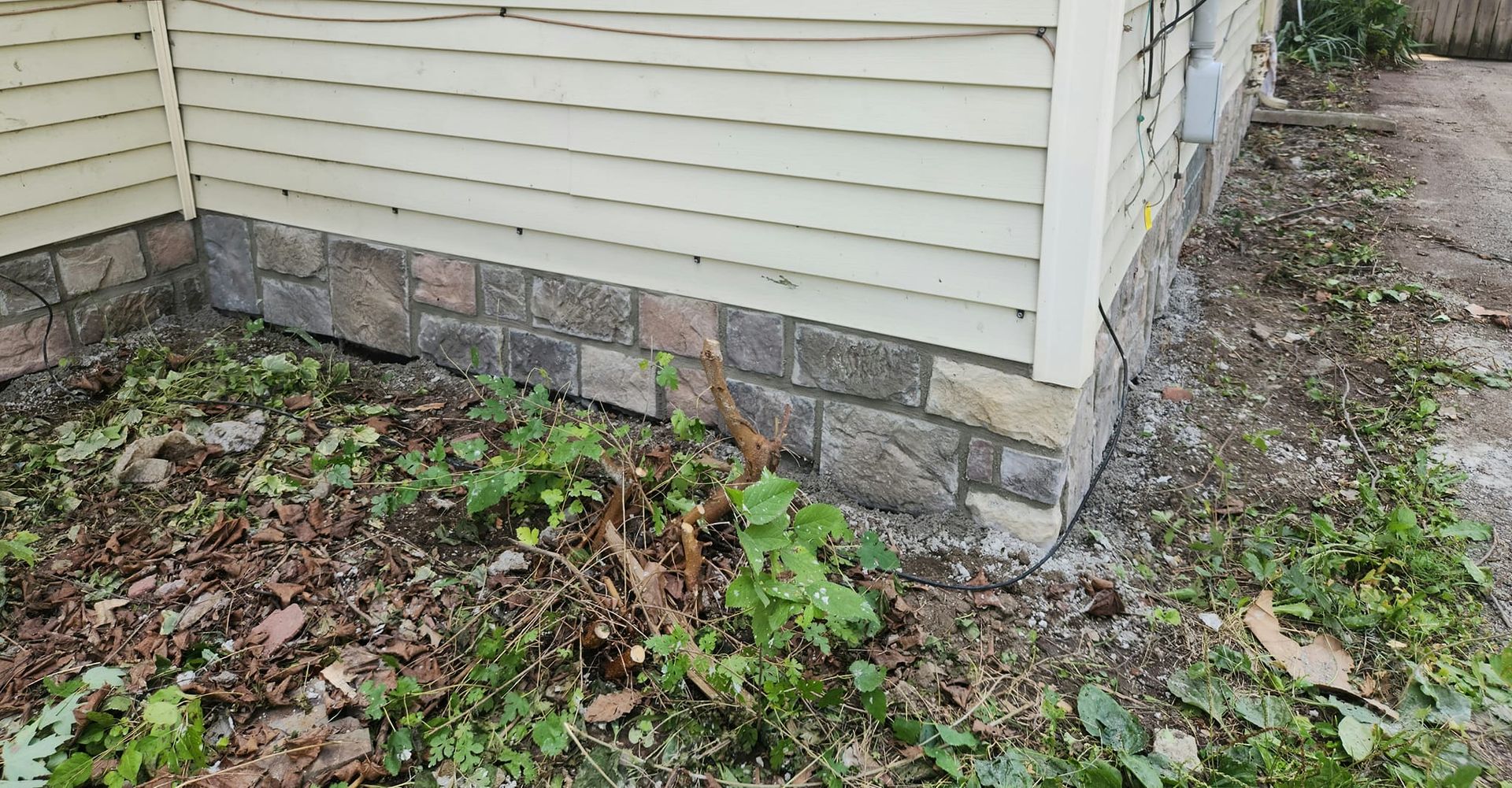 A house with a stone foundation and a white siding.