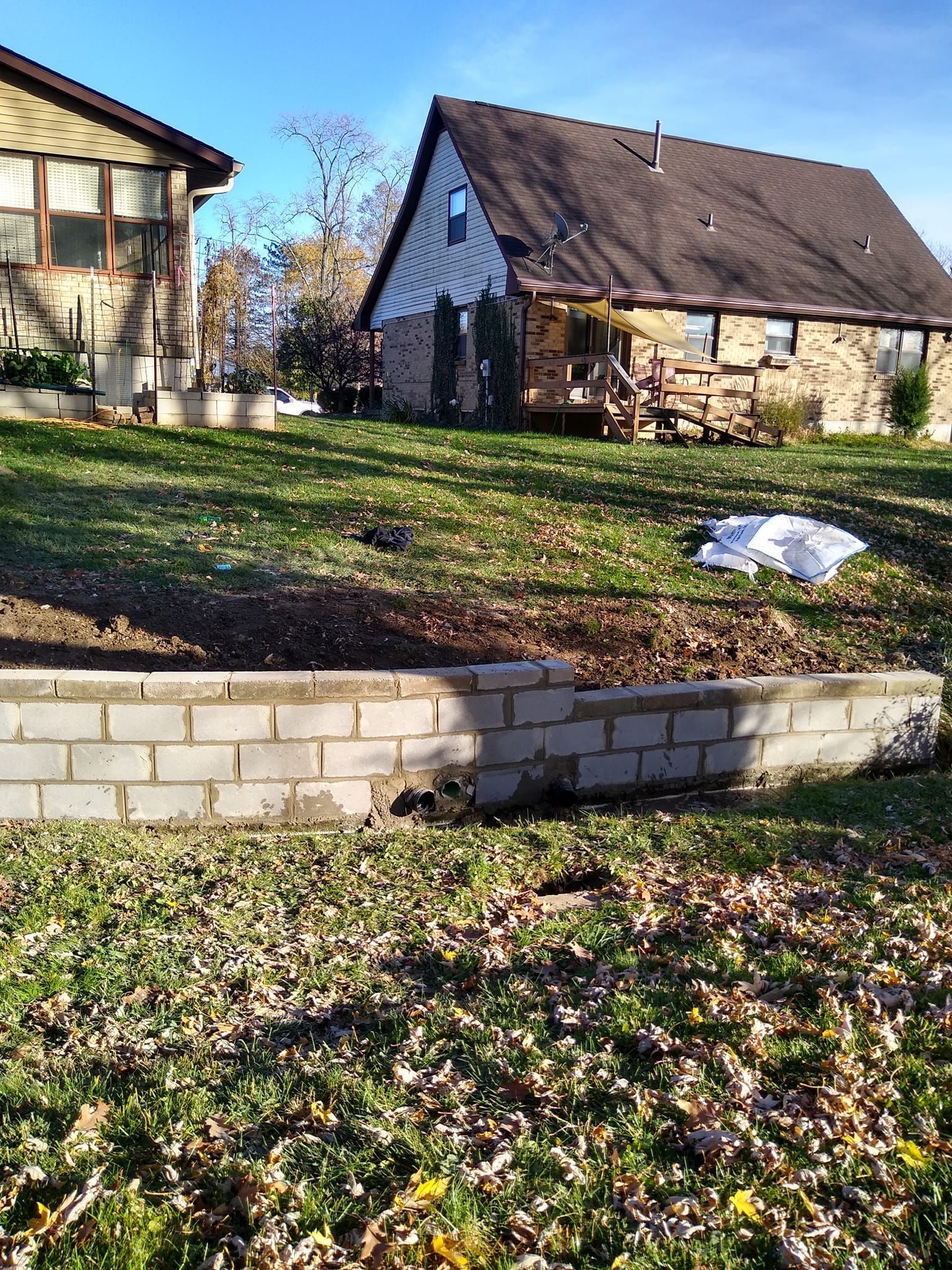 A house is sitting on top of a grassy hill next to a brick wall.