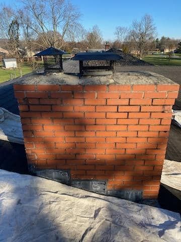 A brick chimney is sitting on top of a roof.