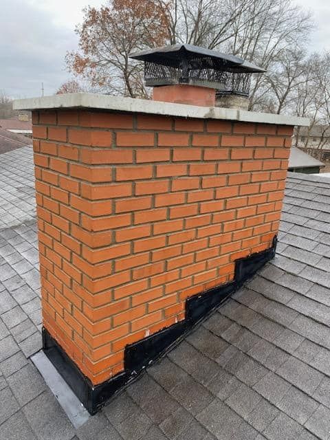 A brick chimney is sitting on top of a roof.