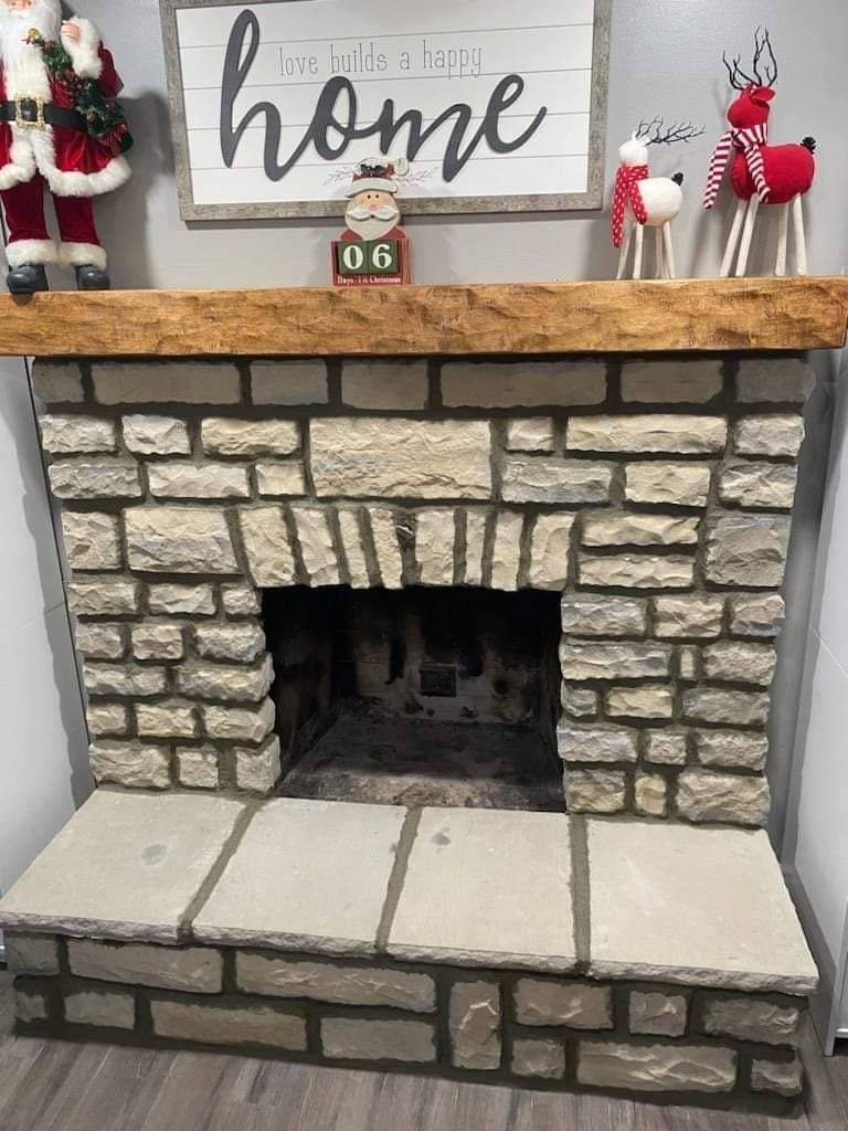A brick fireplace with a wooden mantle and a sign above it.