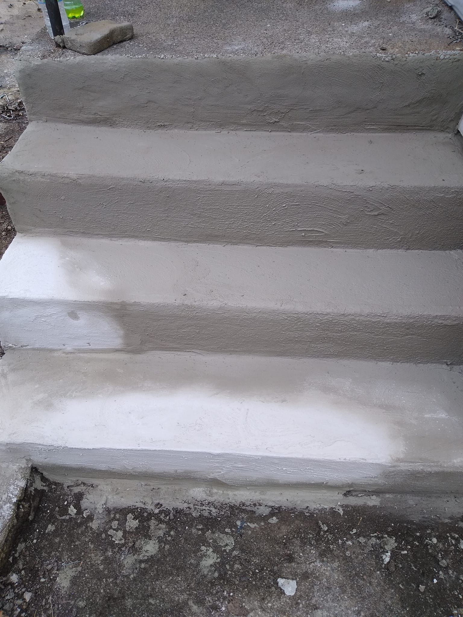 A close up of a set of concrete stairs being painted white.