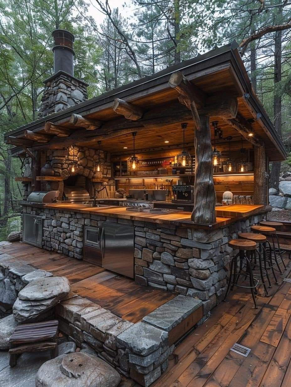 A large outdoor kitchen with a stone counter top and stainless steel appliances.